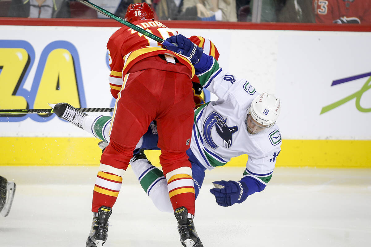 Vancouver Canucks’ Jason Dickinson, right, is checked by Calgary Flames’ Nikita Zadorov during second period NHL pre-season hockey action in Calgary, Friday, Oct. 1, 2021.THE CANADIAN PRESS/Jeff McIntosh