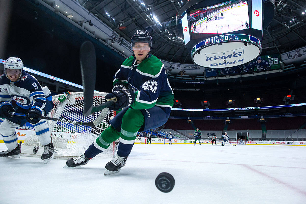 Vancouver Canucks’ Elias Pettersson (40), of Sweden, reaches for the puck in front of Winnipeg Jets’ Andrew Copp (9) during the second period of an NHL hockey game in Vancouver, on Friday, February 19, 2021. THE CANADIAN PRESS/Darryl Dyck
