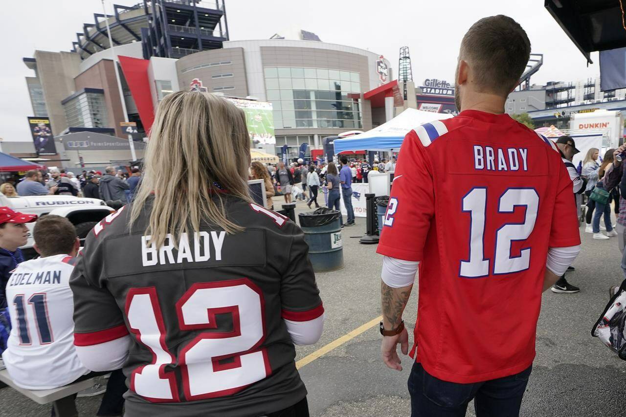 Melissa Zaske, left, of Vancouver, wears Tom Brady’s current Tampa Bay Buccaneers jersey while walking with her husband Derek, who wears Tom Brady’s old New England Patriots jersey, prior to an NFL football game between the New England Patriots and Tampa Bay Buccaneers, Sunday, Oct. 3, 2021, in Foxborough, Mass. (AP Photo/Steven Senne)