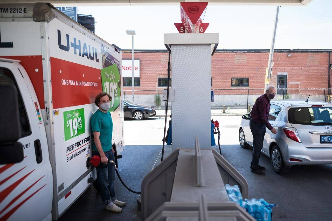 People pump gas into their vehicles at a Esso gas station in Toronto on Tuesday, June 15, 2021. The amount of gas Canadians purchased last year fell to the lowest level in two decades. THE CANADIAN PRESS/Tijana Martin