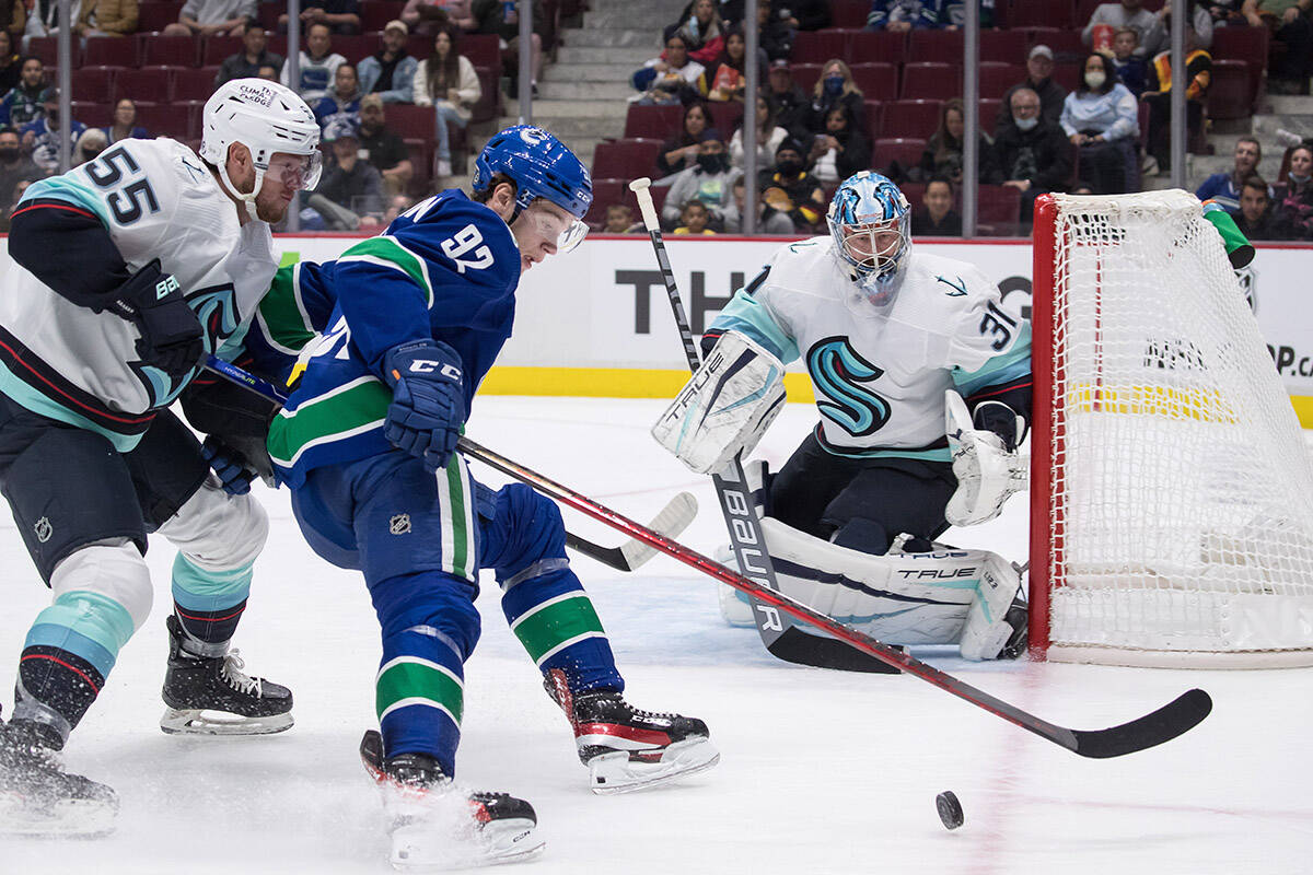 Seattle Kraken’s Jeremy Lauzon (55) checks Vancouver Canucks’ Vasily Podkolzin (92), of Russia, as Seattle’s goalie Philipp Grubauer (31), of Germany, watches during the second period of a pre-season NHL hockey game in Vancouver, on Tuesday, October 5, 2021. THE CANADIAN PRESS/Darryl Dyck