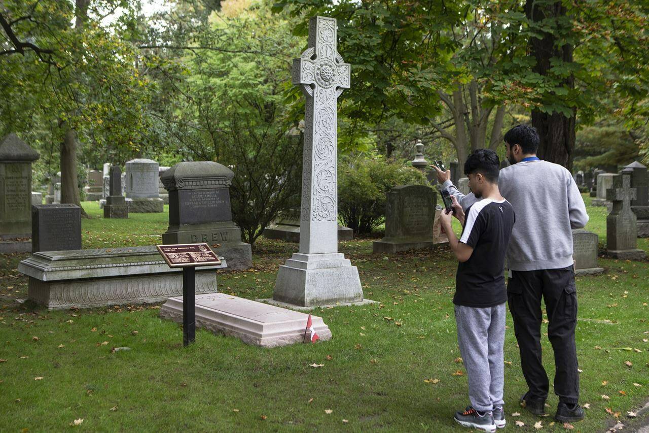 Passers-by stop to take a photo of the grave of former Canadian prime minister Mackenzie King in Toronto’s Mount Pleasant Cemetery on Friday, October 8, 2021. THE CANADIAN PRESS/Chris Young