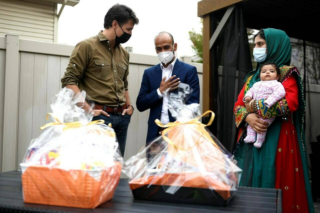 Prime Minister Justin Trudeau speaks with Obaidullah Rahimi, right, his wife Arezoo, and daughter Hawa, 2 months, after assembling care packages for the recently resettled Afghan family for Thanksgiving in Ottawa, on Saturday, Oct. 9, 2021. Obaidullah Rahimi worked at the Canadian Embassy in Afghanistan; his family is one of 22 resettled Afghan families in the Ottawa area. THE CANADIAN PRESS/Justin Tang