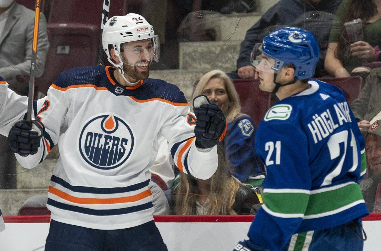 Vancouver Canucks’ Nils Höglander looks on as Edmonton Oilers’ Brendan Perlini celebrates a goal during first period NHL pre-season action in Vancouver, Saturday, October 9, 2021. THE CANADIAN PRESS/Jonathan Hayward