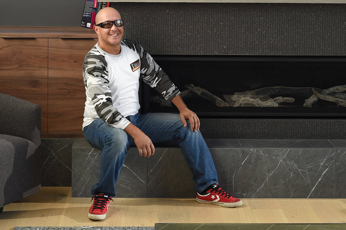 Daniel Caicedo, owner of Victoria Restorations, sits next to a fireplace his company provided the chimney finish for in a Sidney home. Don Denton photograph