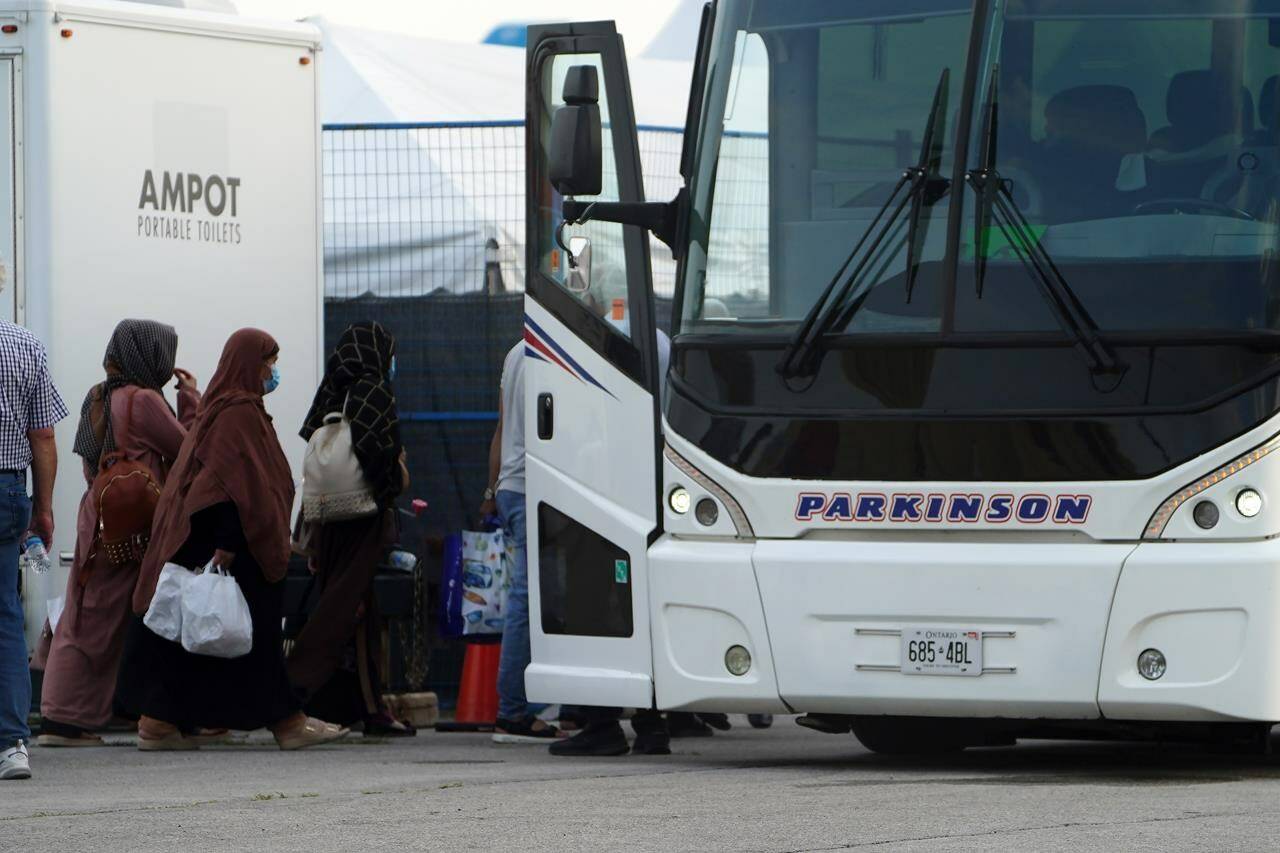 Refugees from Afghanistan and Canadian Citizens board a bus after being processed at Pearson Airport in Toronto, Tuesday, Aug 17, 2021, after arriving indirectly from Afghanistan. THE CANADIAN PRESS/Sean Kilpatrick