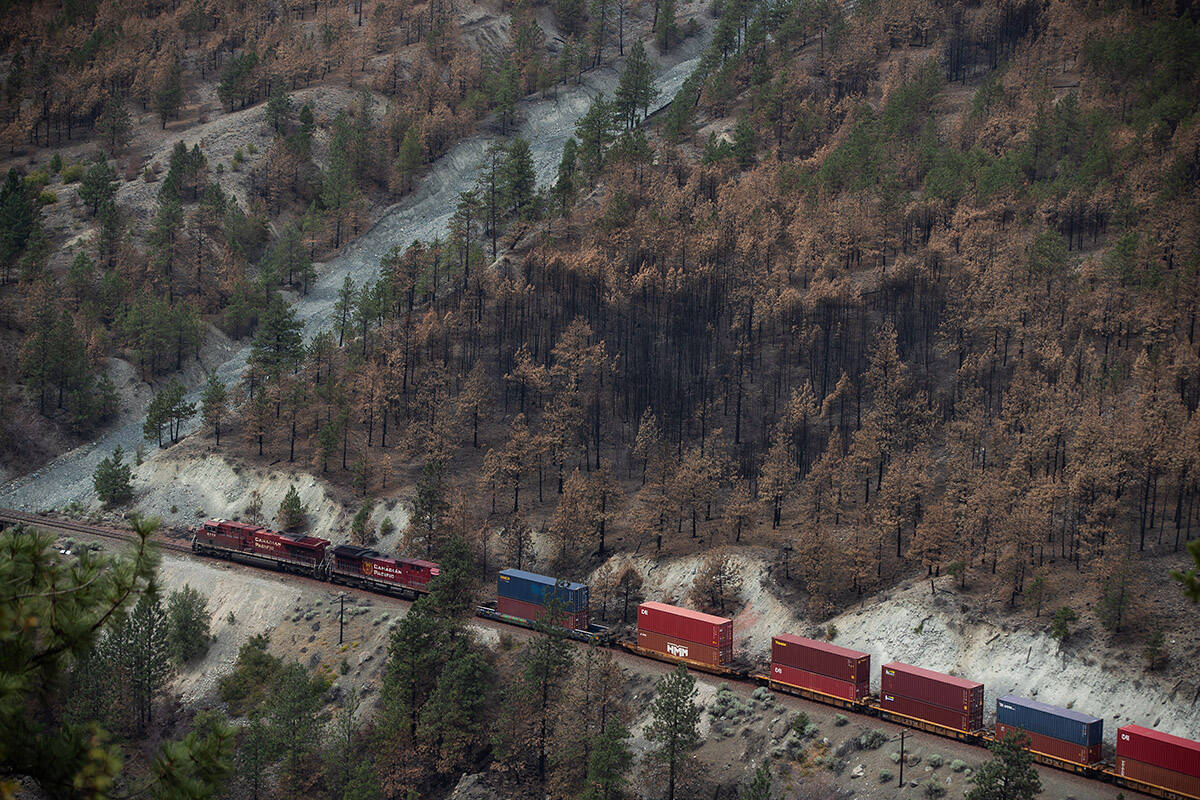 A Canadian Pacific freight train travels on tracks covered with fire retardant in an area burned by wildfire above the Thompson River near Lytton, B.C., on Sunday, August 15, 2021. THE CANADIAN PRESS/Darryl Dyck