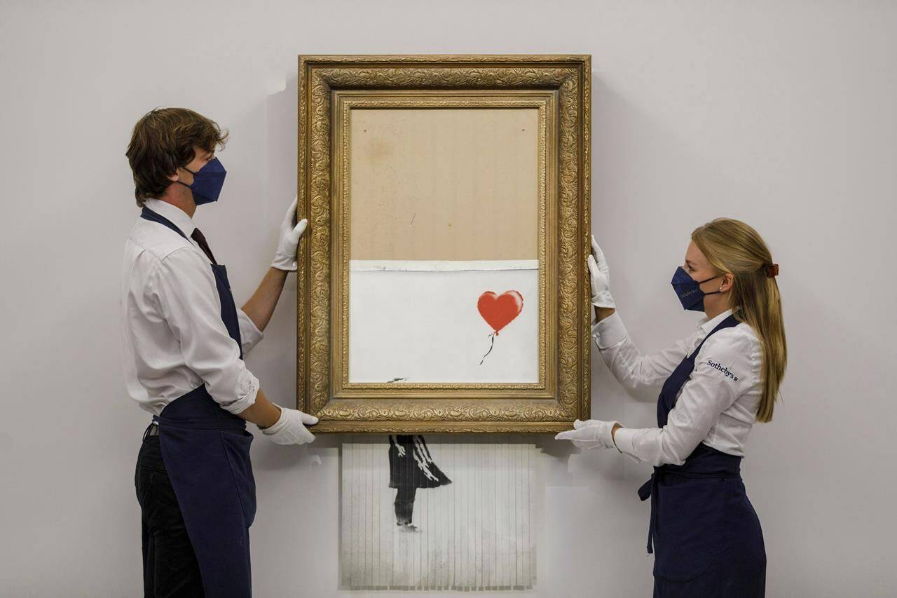 In this handout photo provided by Sotheby’s Auction House, the auction for Banksy’s “Love is the Bin” takes place in London, Thursday, Oct. 14, 2021. A work by British street artist Banksy that sensationally self-shredded just after it sold for $1.4 million has sold again for $25.4 million at an auction on Thursday. “Love is in the Bin” was offered by Sotheby’s in London, with a presale estimate of $5.5 million to $8.2 million. (Sotheby’s Auction House via AP)