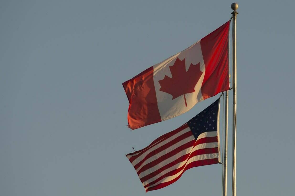 The Canadian and American flags are seen on top of the Peace Arch is at the Canada/USA border in Surrey, B.C. on March 20, 2020. THE CANADIAN PRESS/Jonathan