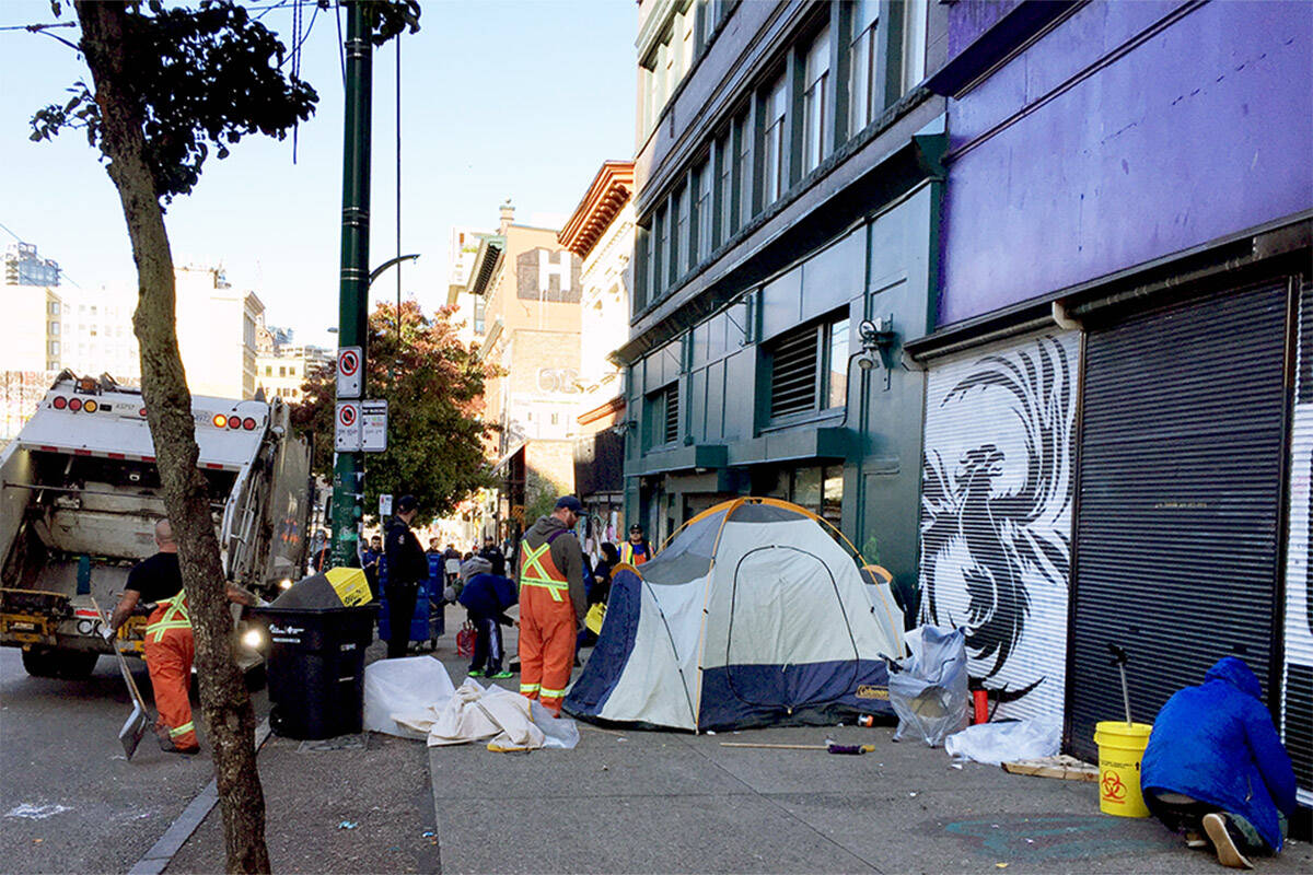 Vancouver Police watch as city workers throw away personal belongings. (Meenakshi Mannoe/Pivot Legal Society)