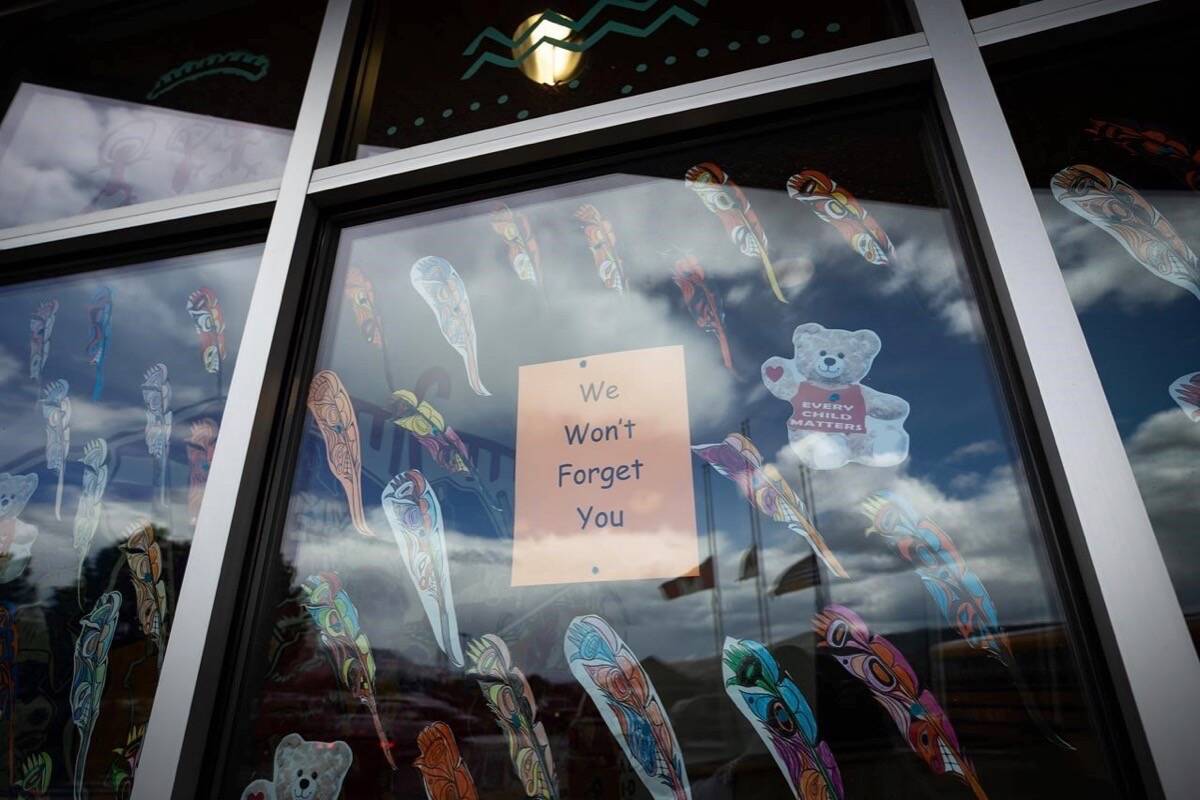 A message is seen on the window of the Sk’elep School of Excellence as the Canadian, Tk’emlups te Secwepemc and B.C. flags are reflected in the window flying at half mast to honour the 215 children whose remains have been discovered buried near the former Kamloops Indian Residential School, in Kamloops, B.C., on Saturday, June 5, 2021. THE CANADIAN PRESS/Darryl Dyck