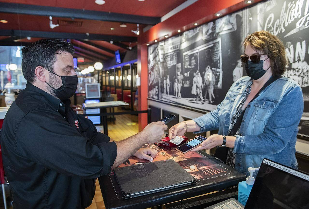 Jimmy Staveris, manager of Dunn’s Famous restaurant, scans the COVID-19 QR code of a customer in Montreal, Wednesday, September 1, 2021. Vaccine passports are emerging as the latest pandemic minefield for restaurant workers in Canada, one riddled with verbal abuse, sexual harassment, racism and forged documents. THE CANADIAN PRESS/Graham Hughes