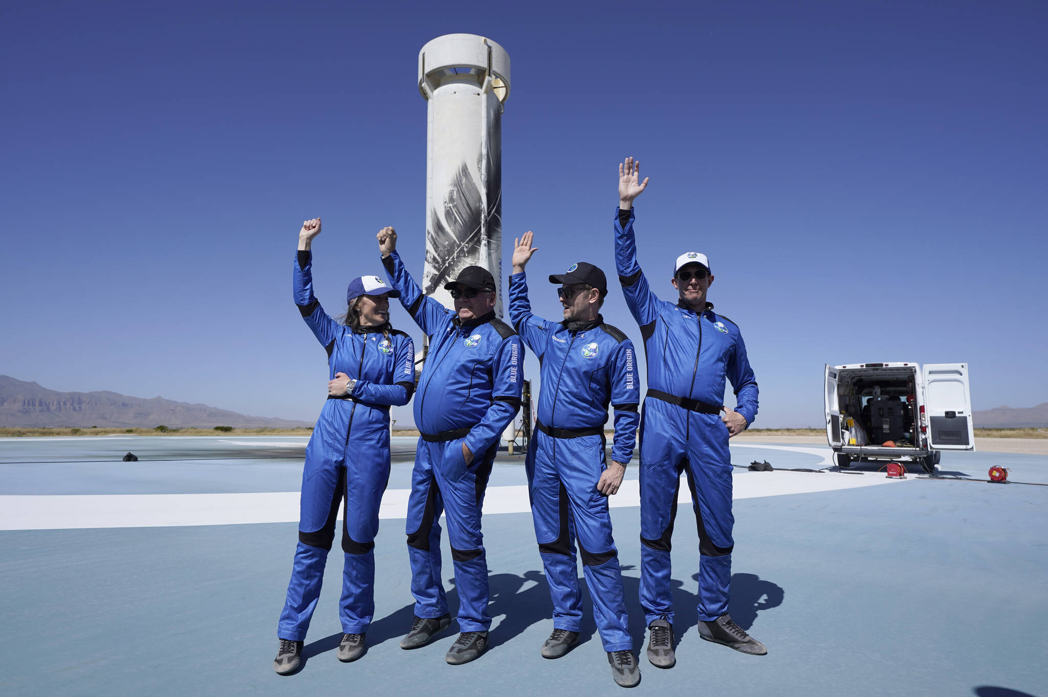 Space passengers from left, Audrey Powers, William Shatner, Chris Boshuizen, and Glen de Vries raise their hands during a media availability at the spaceport near Van Horn, Texas, Wednesday, Oct. 13, 2021. Do you know the name of the spacecraft? (AP Photo / LM Otero)