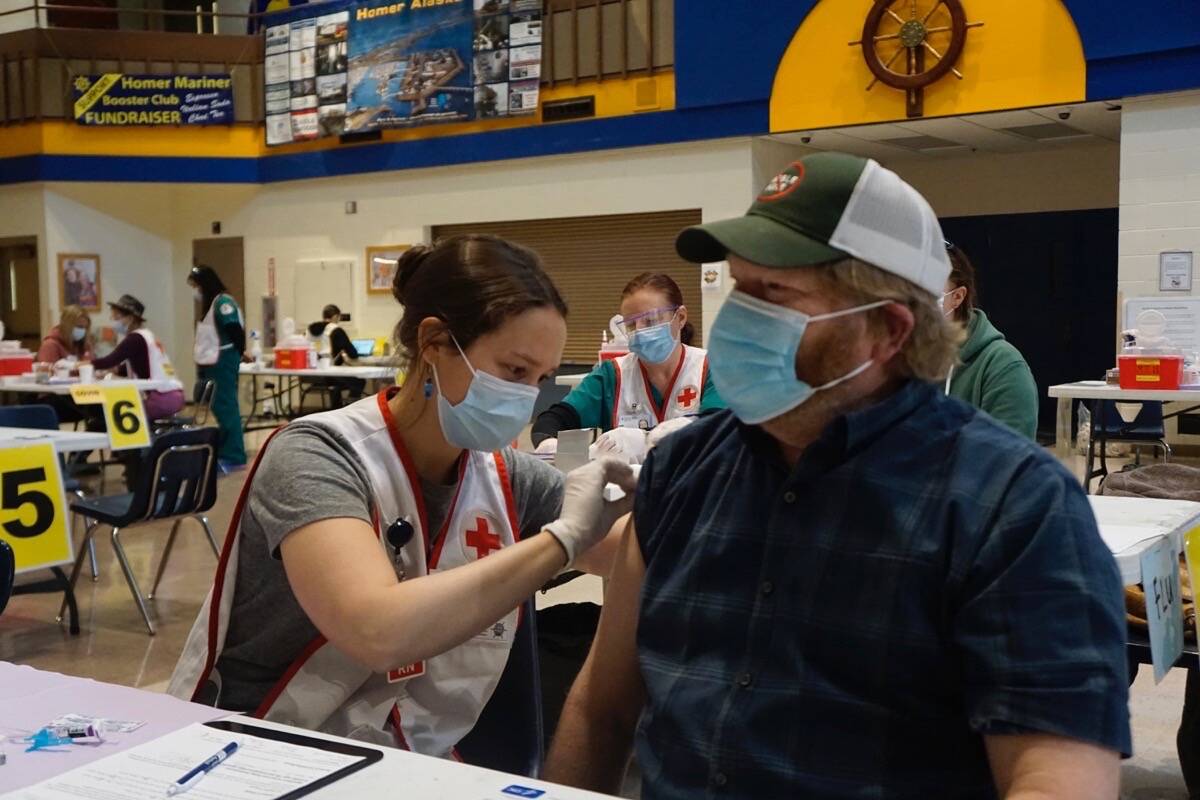 Anna Lewald, left, a registered nurse at South Peninsula Hospital, gives Dave Aplin, right, an influenza vaccine at a flu and Pfizer COVID-19 vaccine clinic Friday, Oct. 15, 2021, at Homer High School in Homer, Alaska. (Photo by Michael Armstrong/Homer News)