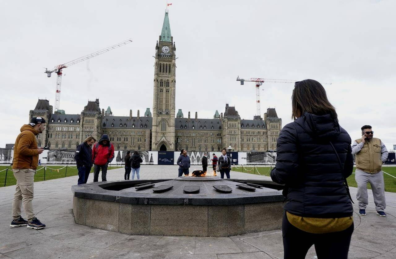 Visitors and tourists to Parliament Hill stand around the Centennial flame on Parliament Hill, in Ottawa, Friday, Oct. 22, 2021. A Parliament Hill memorial to Indigenous children who never returned from residential schools has been dismantled. THE CANADIAN PRESS/Adrian Wyld
