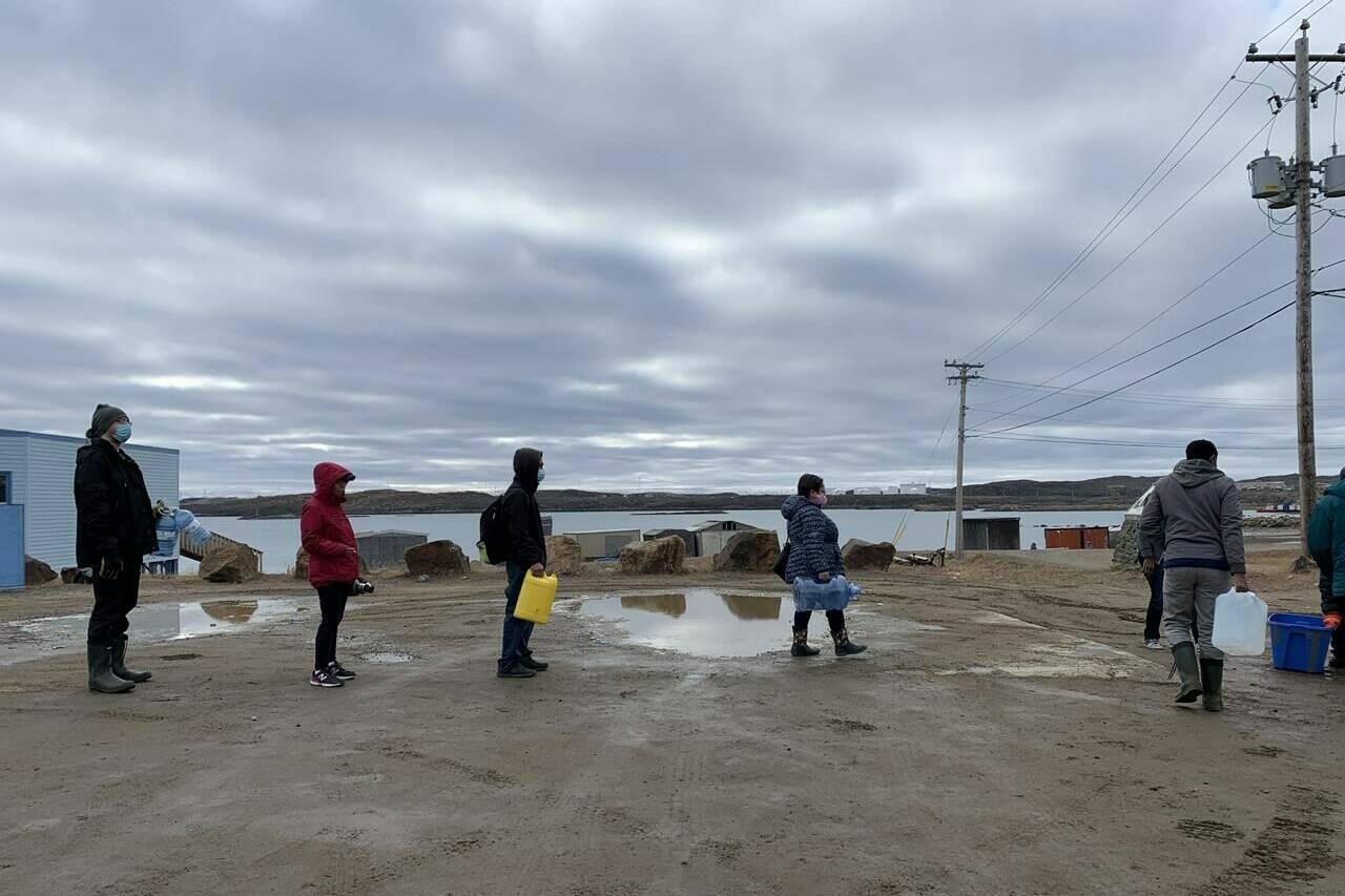 Residents line up to fill containers with potable water in Iqaluit, Nunavut on Thursday, Oct. 14, 2021. The City of Iqaluit says an old underground spill is likely responsible for fuel that is contaminating the city’s tap water. THE CANADIAN PRESS/Emma Tranter