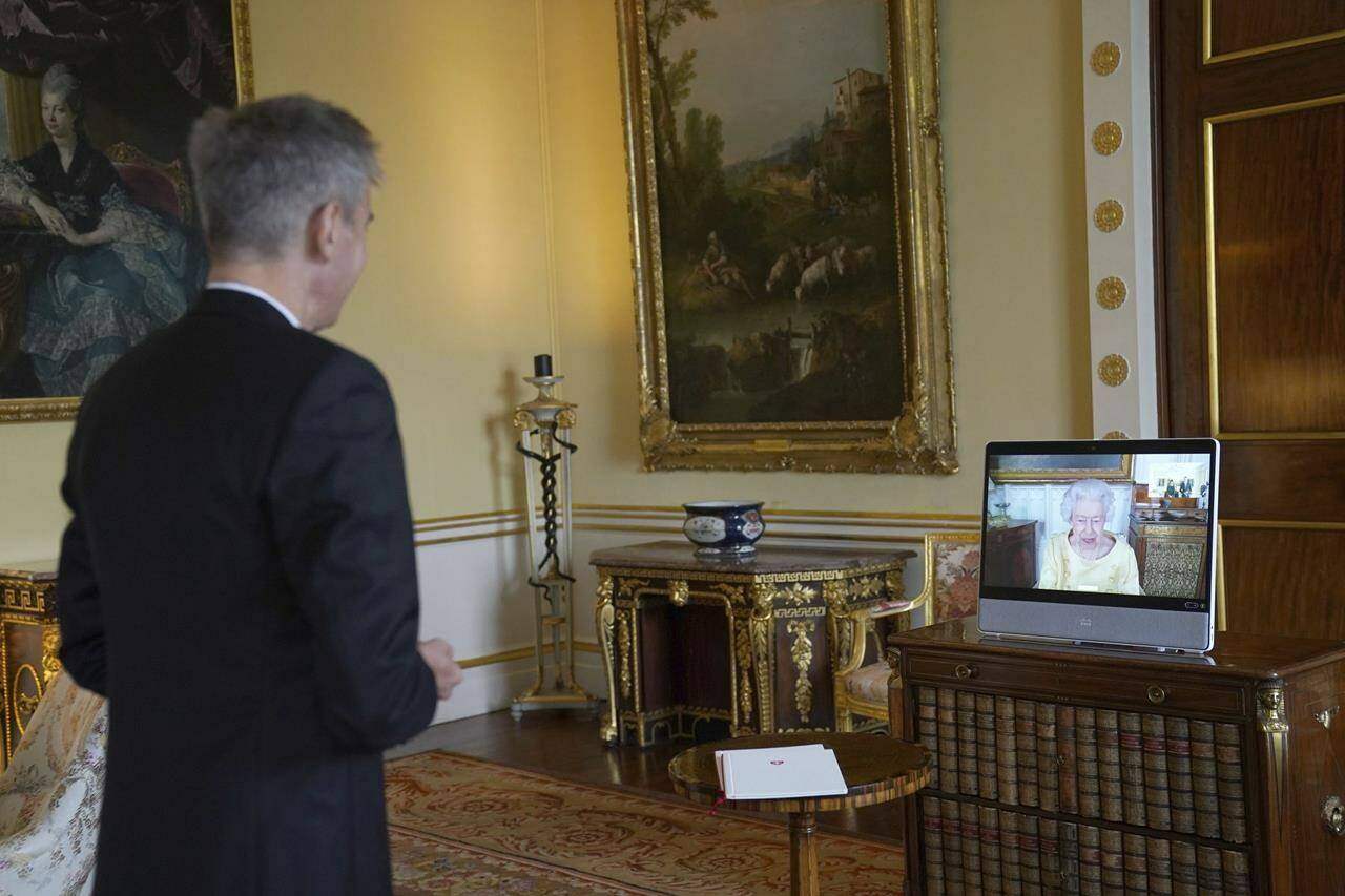 Queen Elizabeth II appears on a screen via videolink from Windsor Castle, where she is in residence, during a virtual audience to receive the Ambassador from the Swiss Confederation, Markus Leitner, at Buckingham Palace, London, Tuesday, Oct. 26, 2021. (Victoria Jones/Pool via AP)