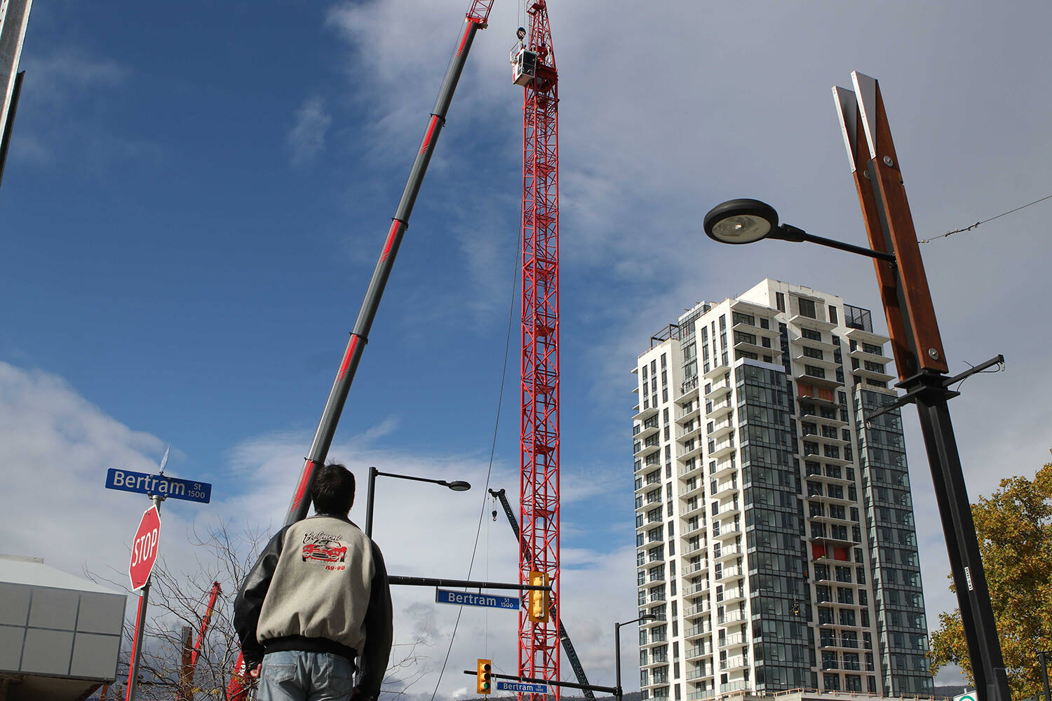A man watches as a new tower crane is assembled in downtown Kelowna on Oct 26, 2021. (Aaron Hemens/Capital News)