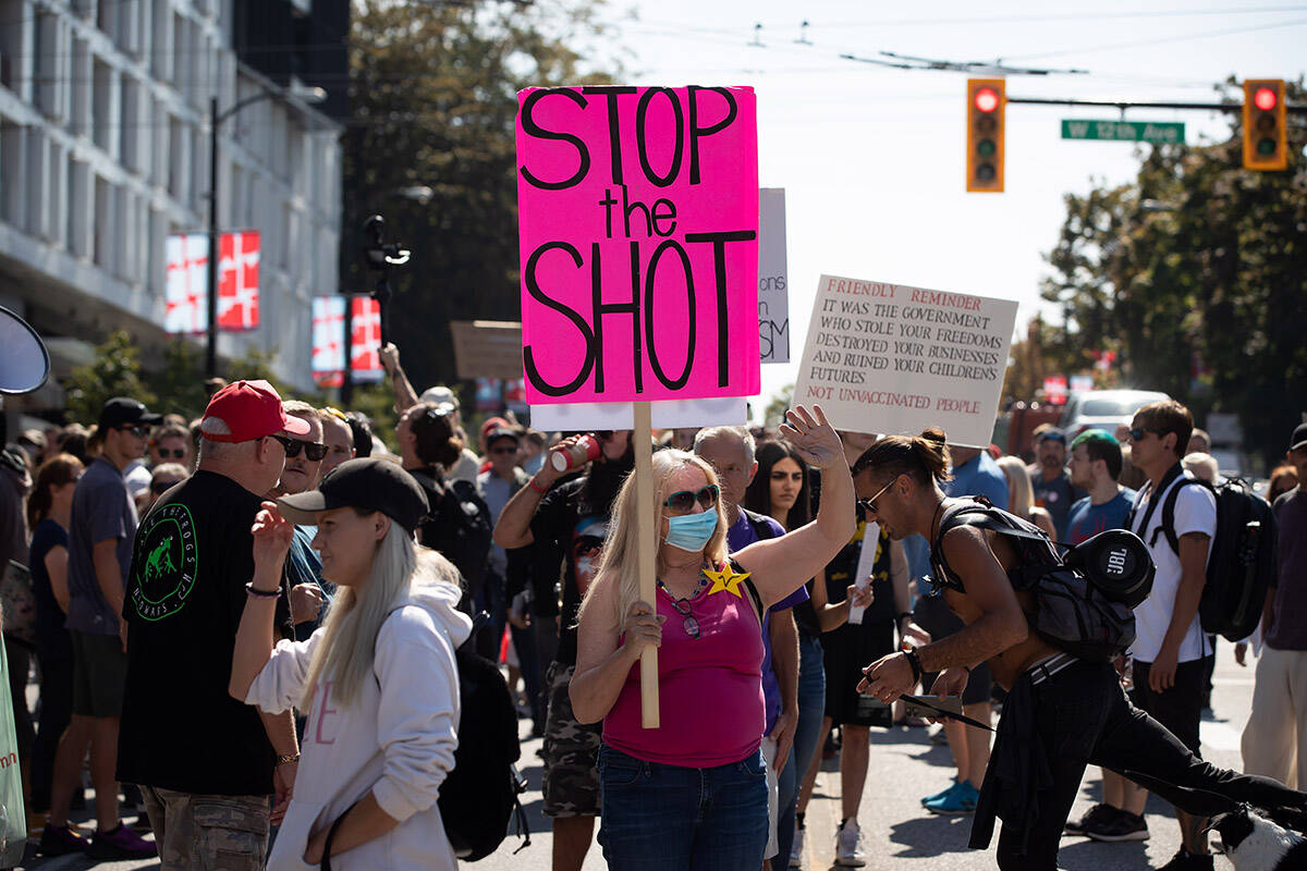 FILE – A woman wearing a face mask holds a sign while attending a rally and march organized by people opposed to COVID-19 vaccination passports and public health measures, in Vancouver, on Wednesday, September 8, 2021. THE CANADIAN PRESS/Darryl Dyck