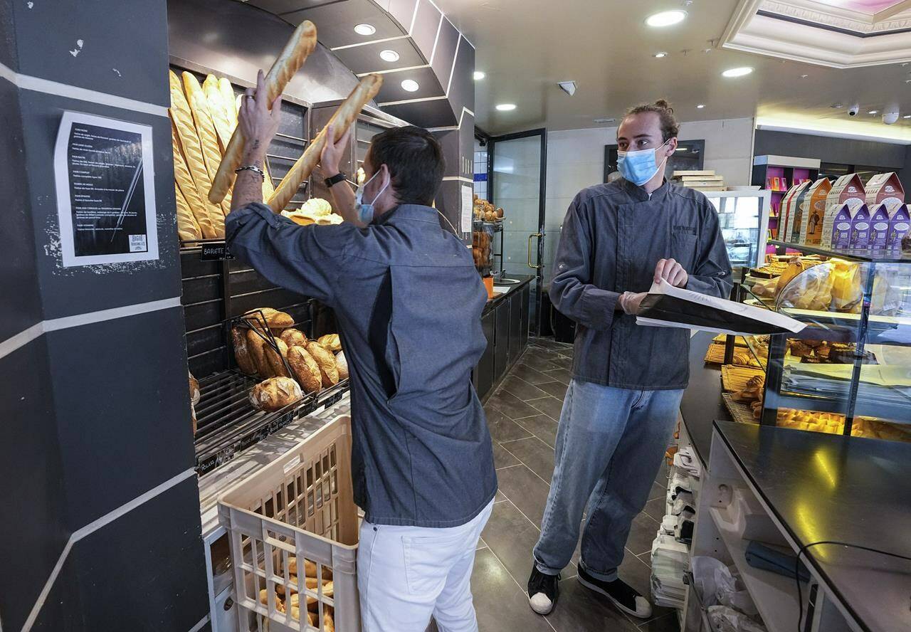 Bakers Ludovic Laurent, left, and Hugo Hardy Baguettes prepares baguettes to be sold at Bigot bakery in Versailles, west of Paris, Tuesday, Oct. 26, 2021. A worldwide increase in wheat prices after bad harvests in Russia is forcing French bakers to raise the price of that staple of life in France the baguette. Boulangeries around France have begun putting up signs warning their customers of an increase in the price of their favourite bread due to rising costs. (AP Photo/Michel Euler