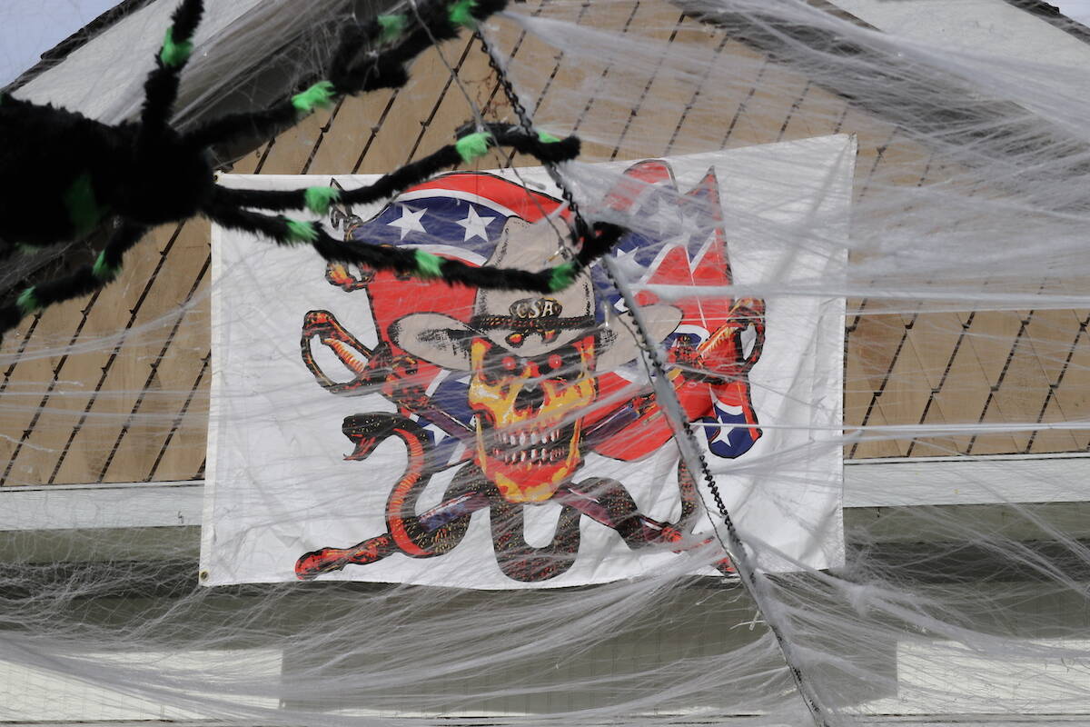 A flag with a skeleton cowboy in front of a flying confederate flag hangs from a Bay Avenue home on Oct. 27, 2021. Part of the Halloween decoration was reported by other Kelowna media to have included a prop of a figure hanging from a tree on public property in front of the home, sparking a public reaction. (Joshua Fischlin/Black Press Media)
