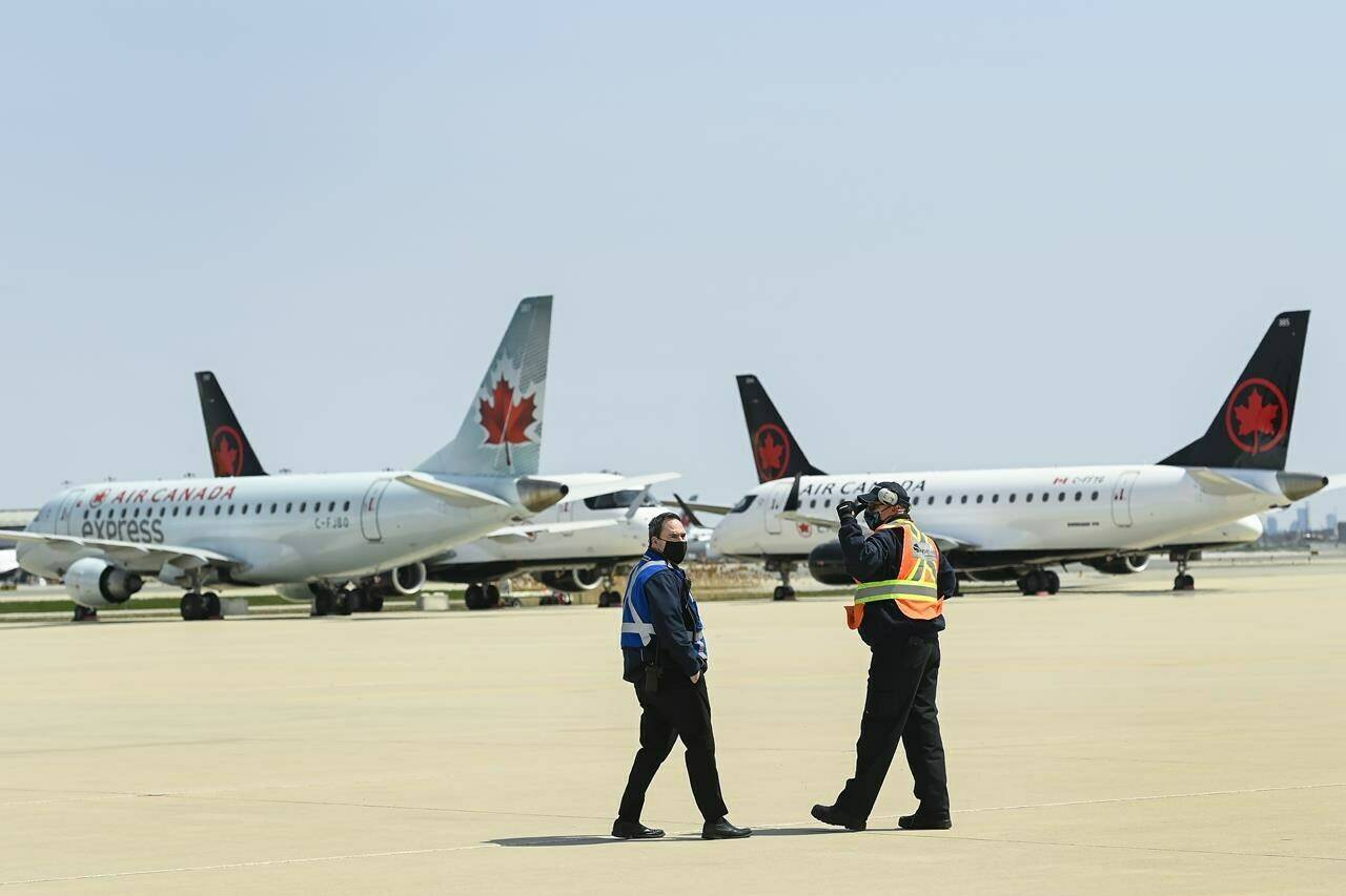 Airline ground crew walks past grounded Air Canada planes as they sit on the tarmac at Pearson International Airport during the during the COVID-19 pandemic in Toronto on Tuesday, April 27, 2021. The airline industry has started down a long runway to recovery after the world’s worst health crisis decimated their operations. THE CANADIAN PRESS/Nathan Denette