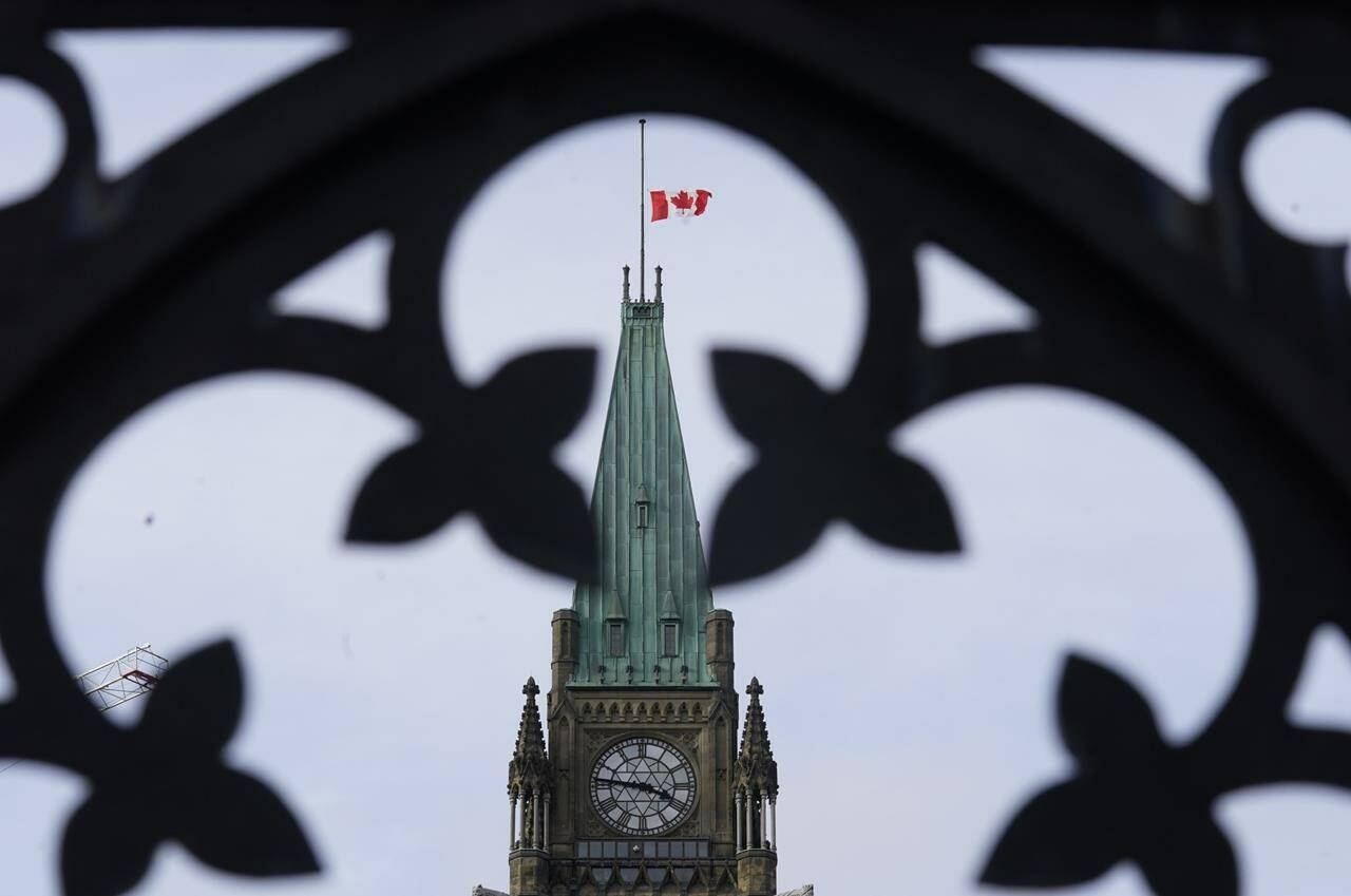 The Canadian flag flies at half mast over the Peace tower and parliament buildings in Ottawa on October 22, 2021. THE CANADIAN PRESS/Adrian Wyld