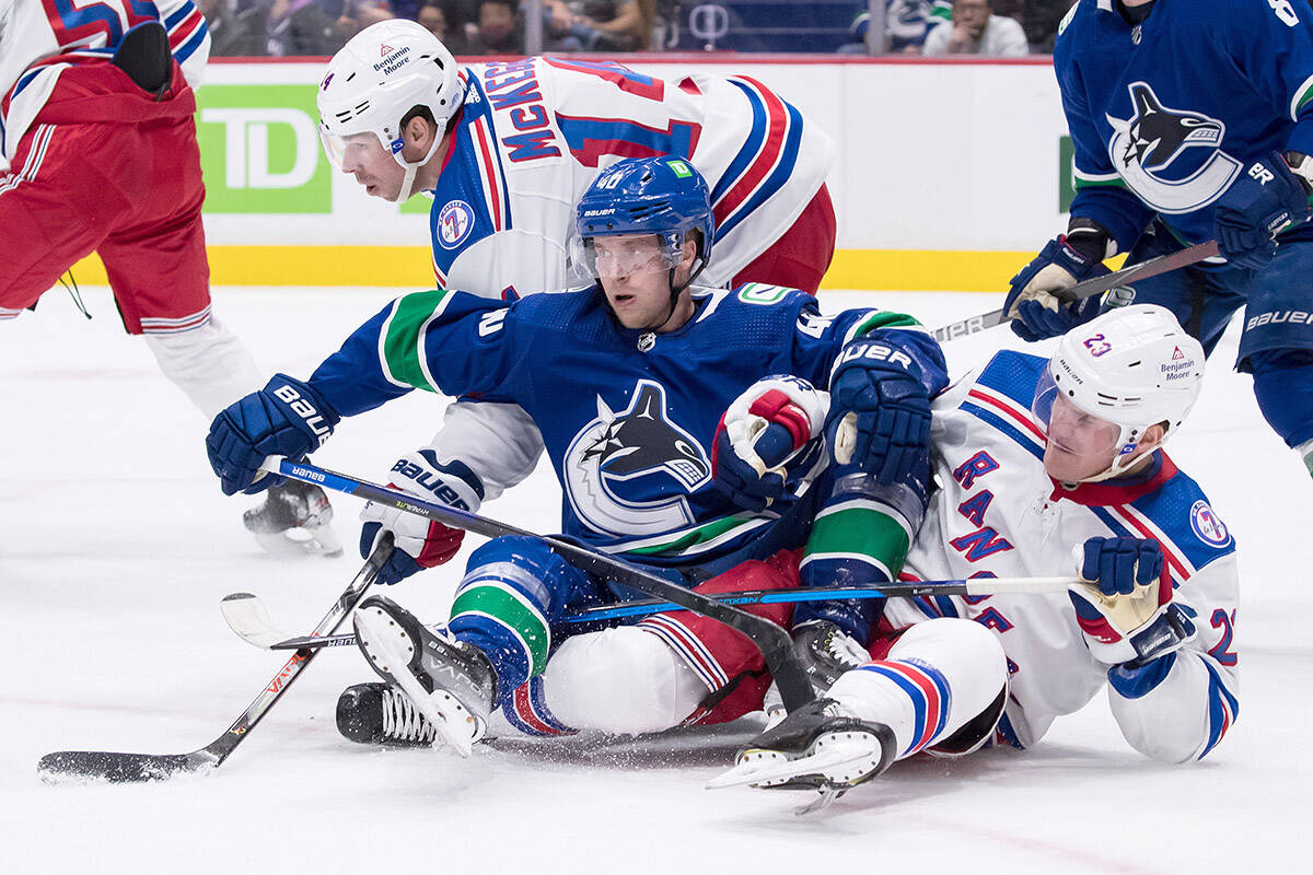 Vancouver Canucks’ Elias Pettersson, centre, of Sweden, collides with New York Rangers’ Greg McKegg, left, and Adam Fox, right, during the second period of an NHL hockey game in Vancouver, on Tuesday, November 2, 2021. THE CANADIAN PRESS/Darryl Dyck