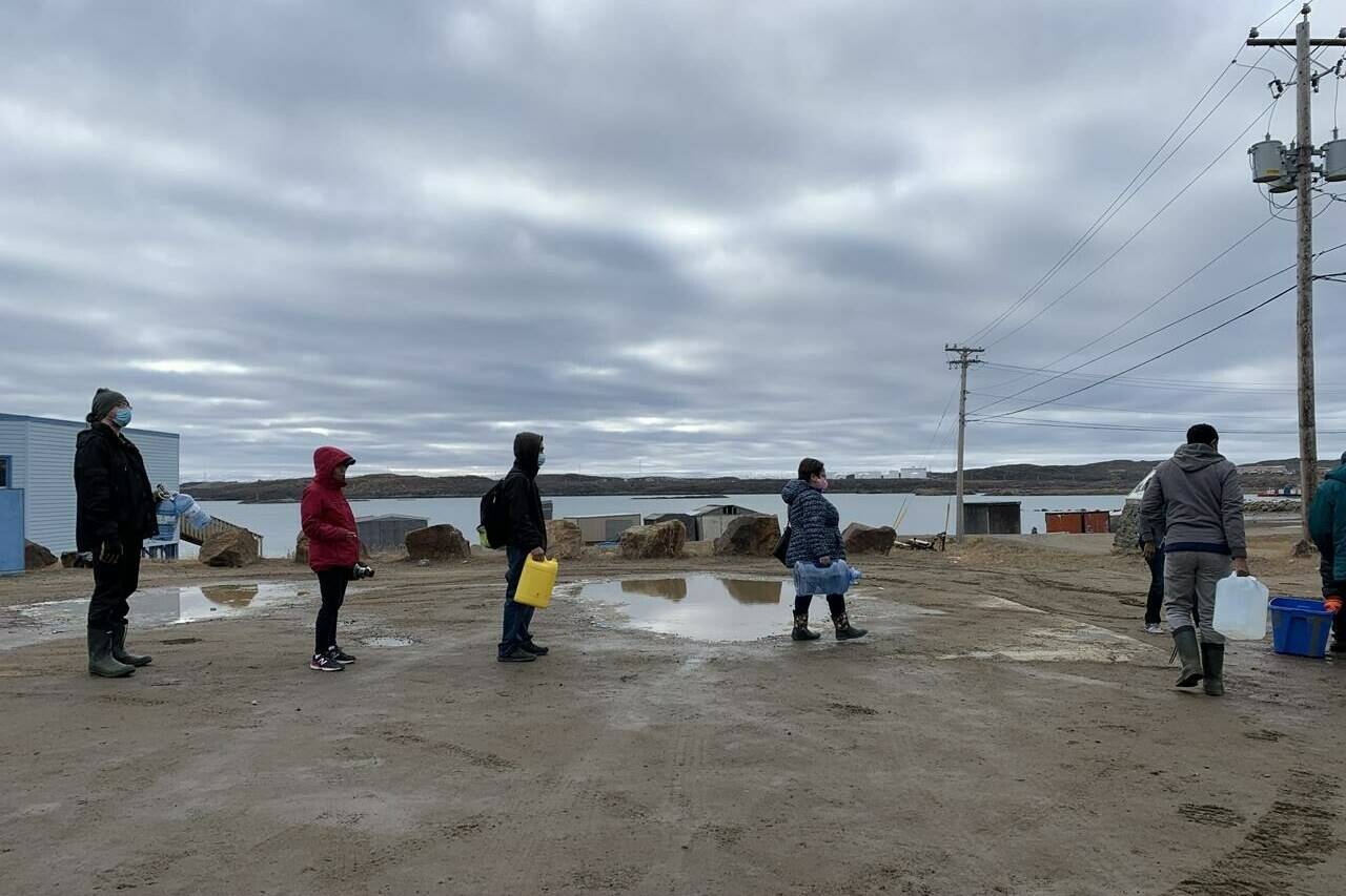 Residents line up to fill containers with potable water in Iqaluit, Nunavut on Thursday, Oct. 14, 2021. The City of Iqaluit says an old underground spill is likely responsible for fuel that is contaminating the city’s tap water. THE CANADIAN PRESS/Emma Tranter