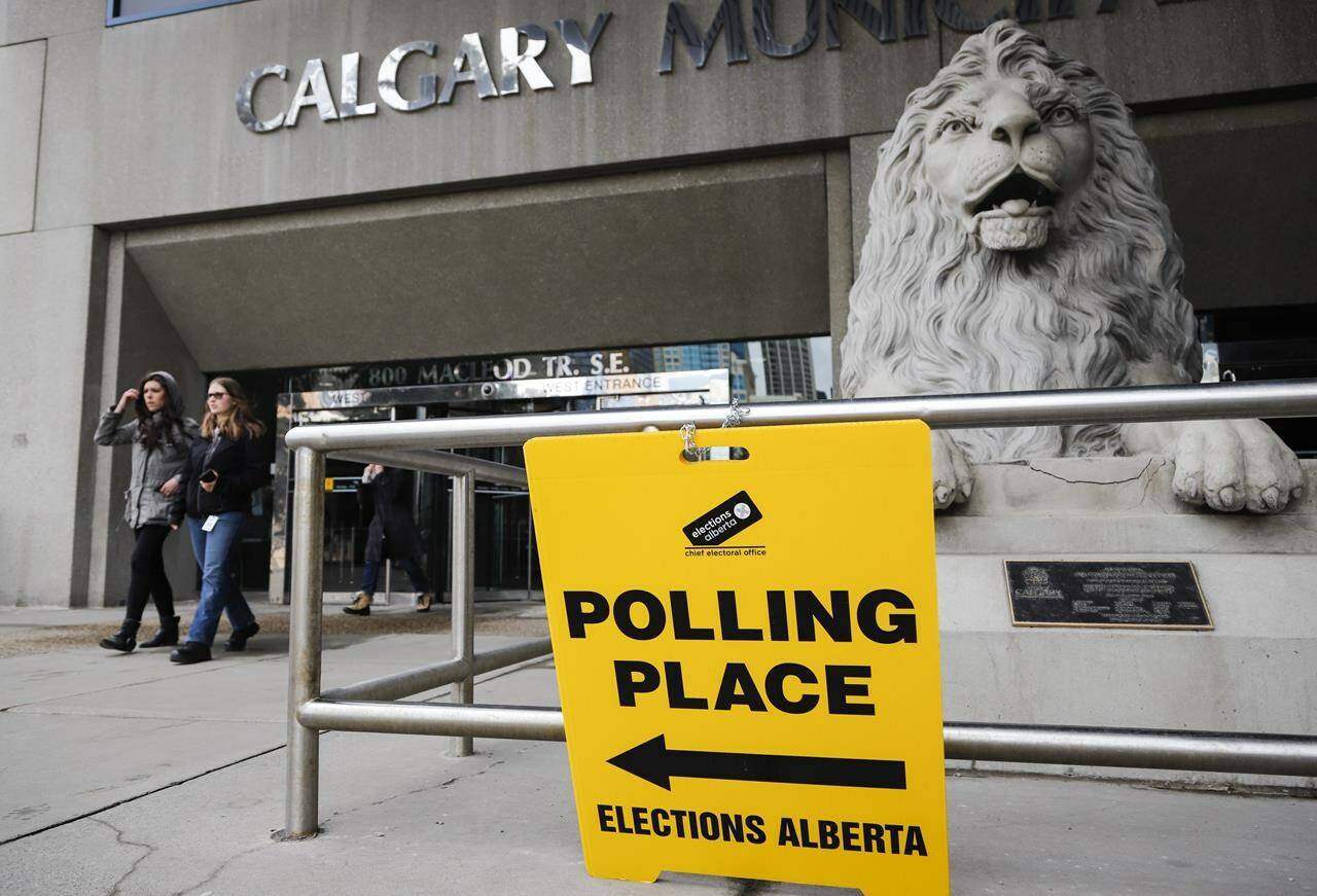 Pedestrians walk past an advance polling station sign outside Calgary city hall on Friday, April 12, 2019. Alberta plans to set a specific day for future provincial elections. A bill introduced by Justice Minister Kaycee Madu proposes the last Monday in May every four years as the day Albertans go to the polls. THE CANADIAN PRESS/Jeff McIntosh