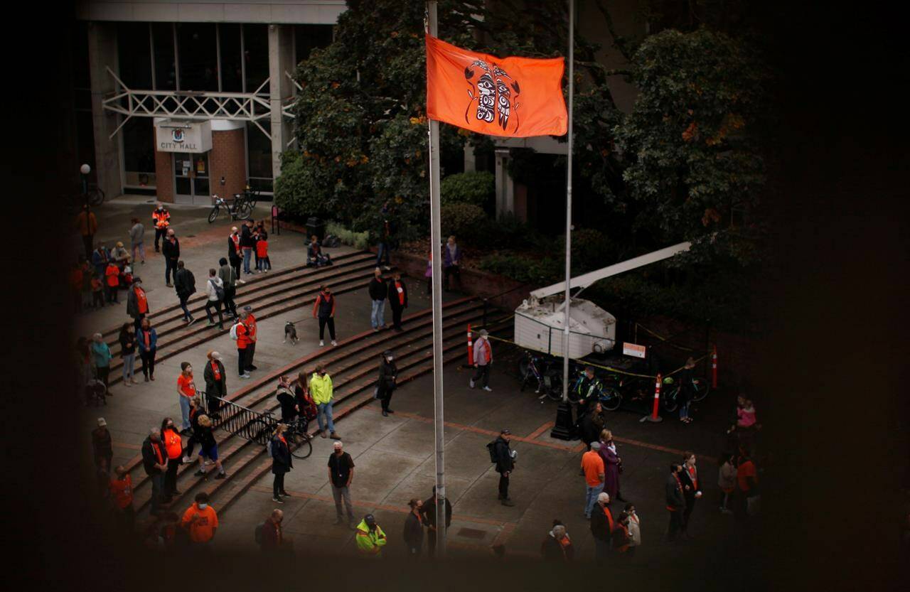 A ceremonial flagged is raised as people attend the Xe xe Smun’ eem-Victoria Orange Shirt Day Every Child Matters ceremony to honour victims of the Canadian Indian residential school system while at Centennial Square in Victoria, Thursday, Sept. 30, 2021. The Assembly of First Nations says it has found a solution to raising the Canadian flag on Remembrance day, while continuing to grieve for Indigenous children who died at residential schools. THE CANADIAN PRESS/Chad Hipolito