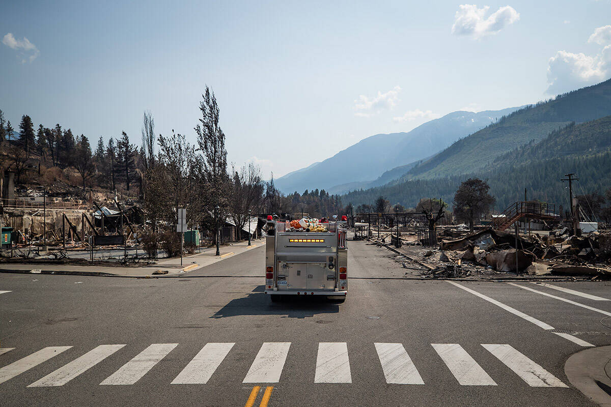 A fire truck leads a bus down Main Street past damaged structures during a media tour in Lytton, B.C., on Friday, July 9, 2021, after a wildfire destroyed most of the village on June 30. THE CANADIAN PRESS/Darryl Dyck