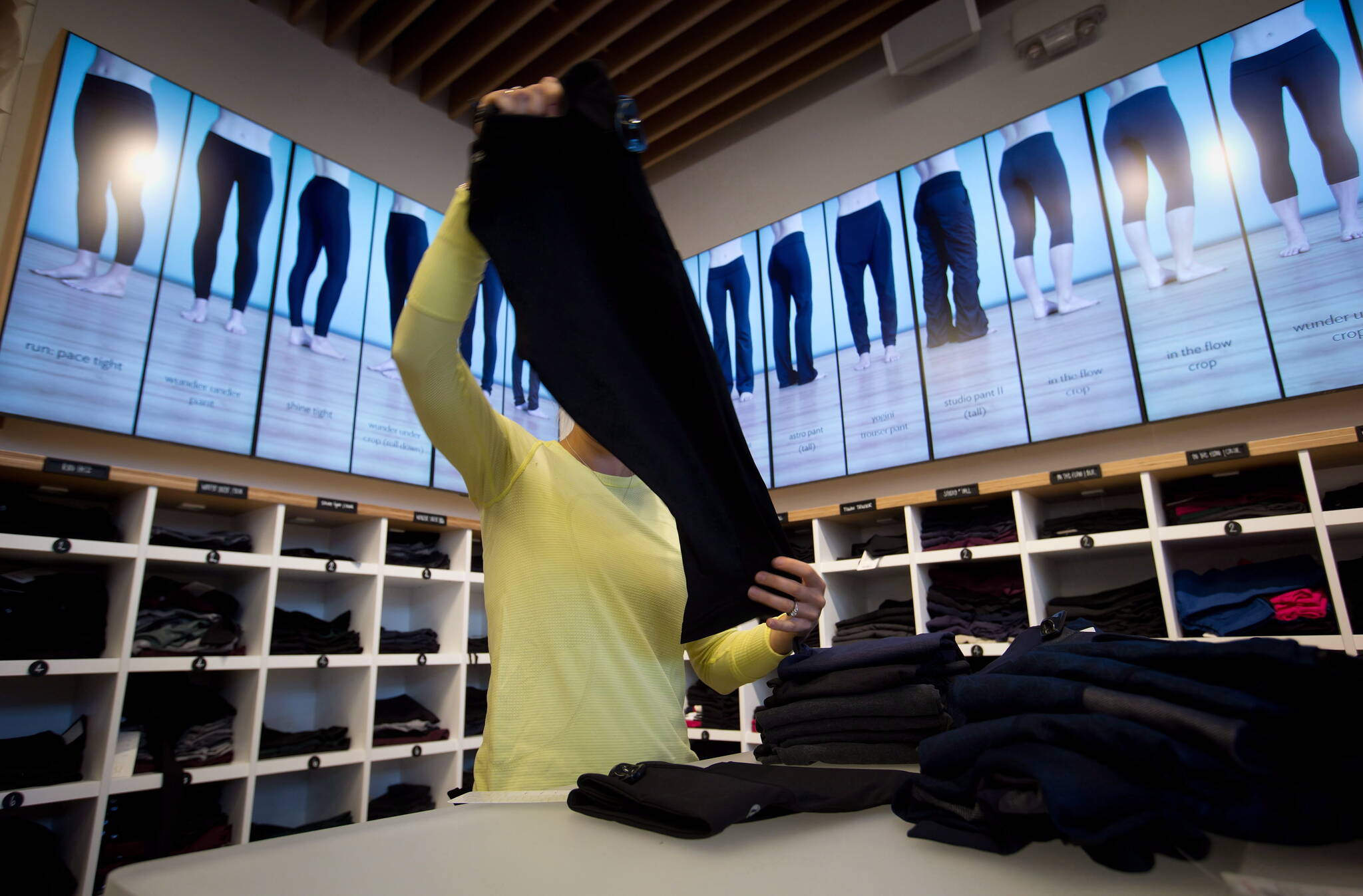 An employee folds yoga pants as the types of pants are animated and displayed on digital screens instead of mannequins at a Lululemon Athletica store in Vancouver. THE CANADIAN PRESS/Darryl Dyck