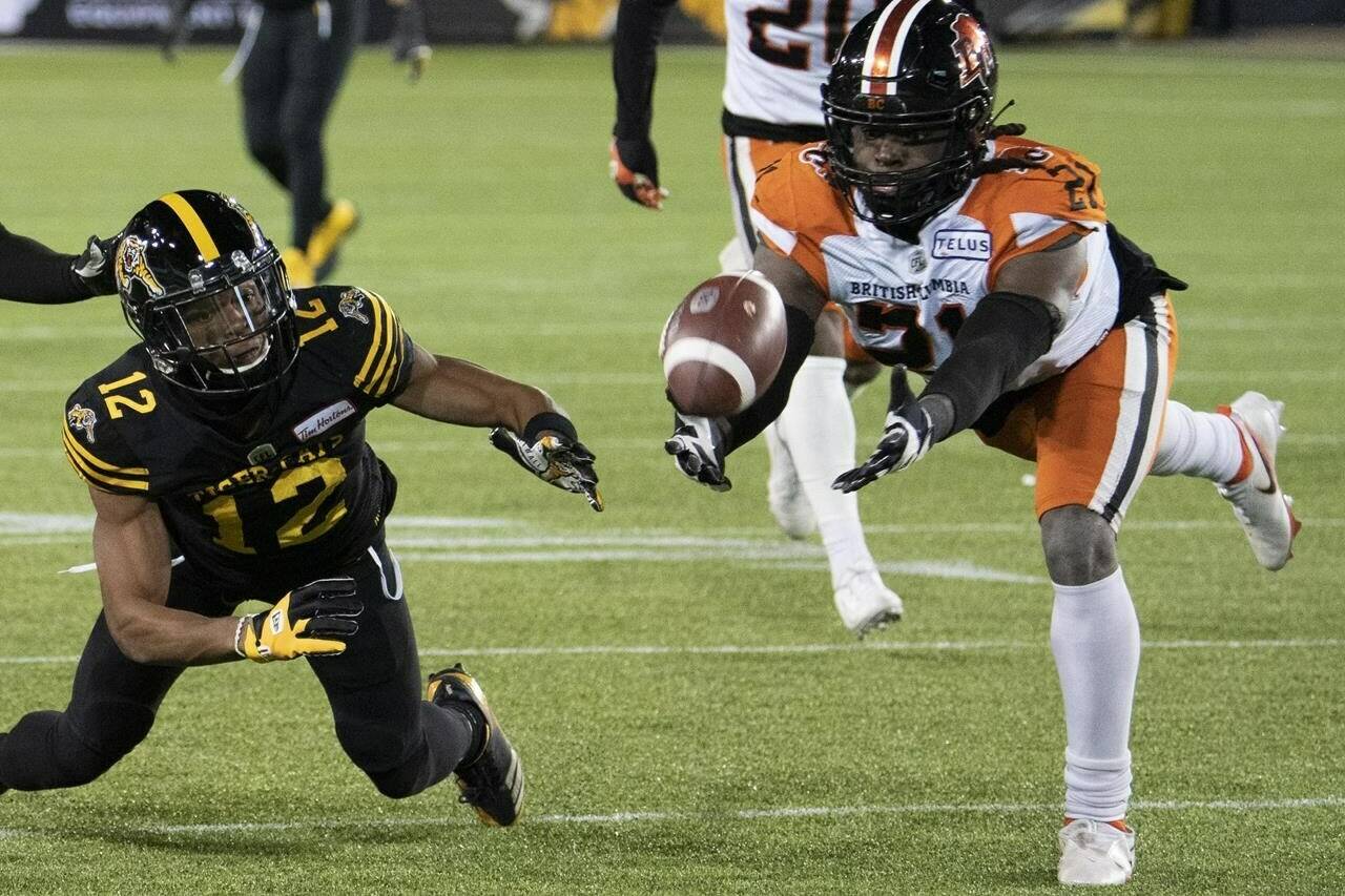 Hamilton Tiger Cats wide receiver Tim White (12) and B.C. Lions linebacker Jordan Williams (21) dive for a loose ball during second half CFL football game action in Hamilton, Ont. on Friday, November 5, 2021. THE CANADIAN PRESS/Peter Power