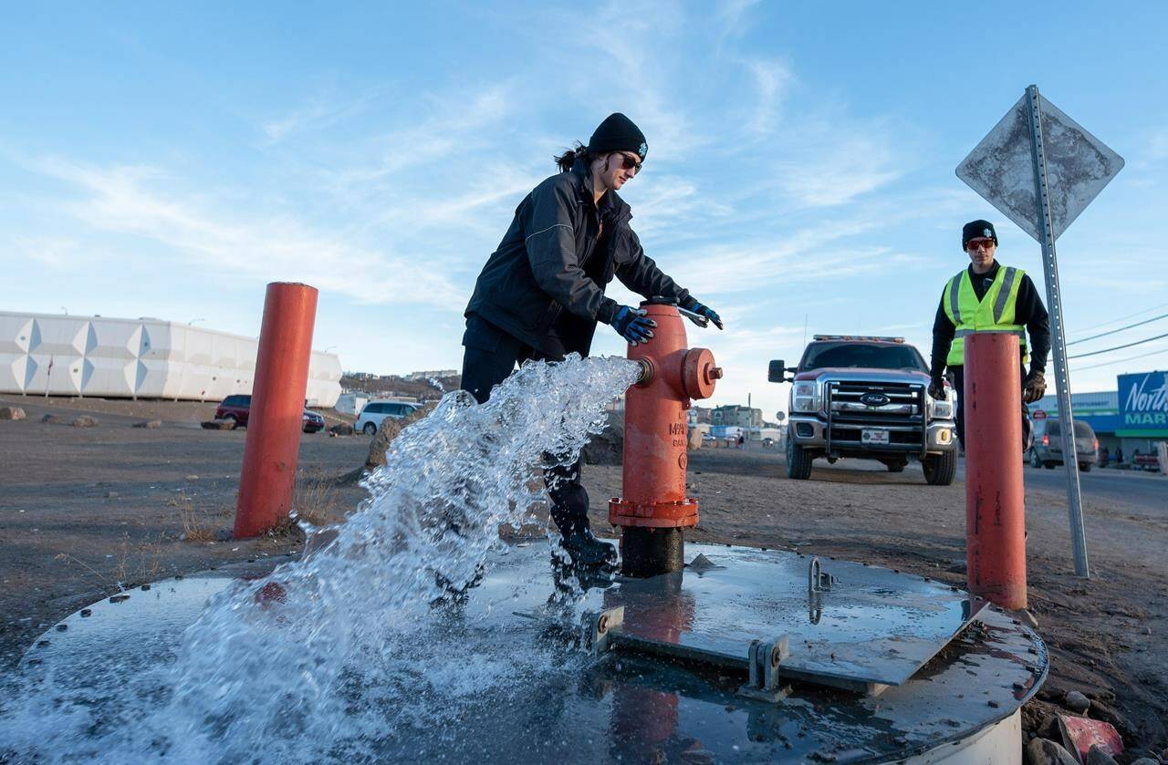 Members of the Iqaluit Fire Department assist with flushing the city’s water pipes in Iqaluit, Nunavut, on Wednesday, Oct. 27, 2021. Engineers say the source of fuel in Iqaluit’s water likely comes from an underground fuel tank built in 1962. THE CANADIAN PRESS/Dustin Patar
