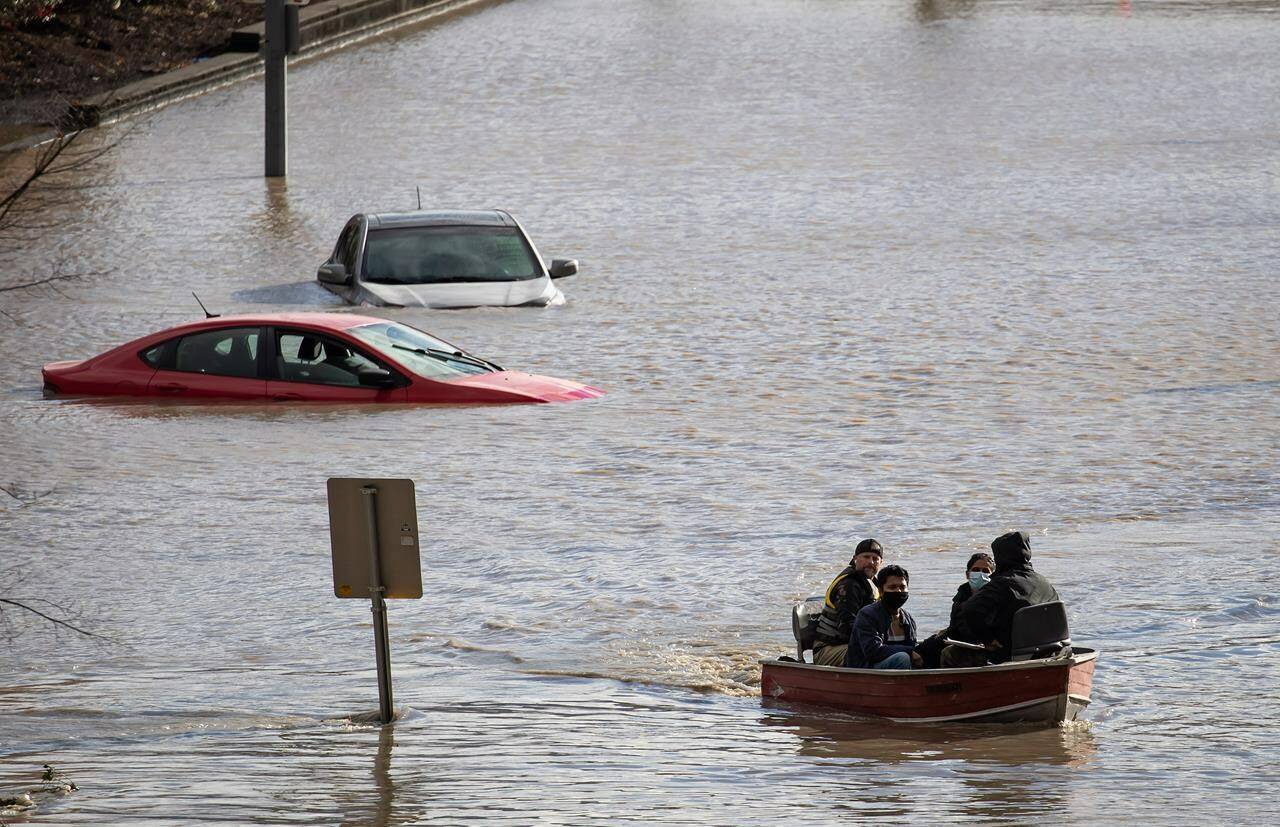 People who were stranded by high water due to flooding are rescued by a volunteer operating a boat in Abbotsford, B.C., on Tuesday, November 16, 2021. THE CANADIAN PRESS/Darryl Dyck