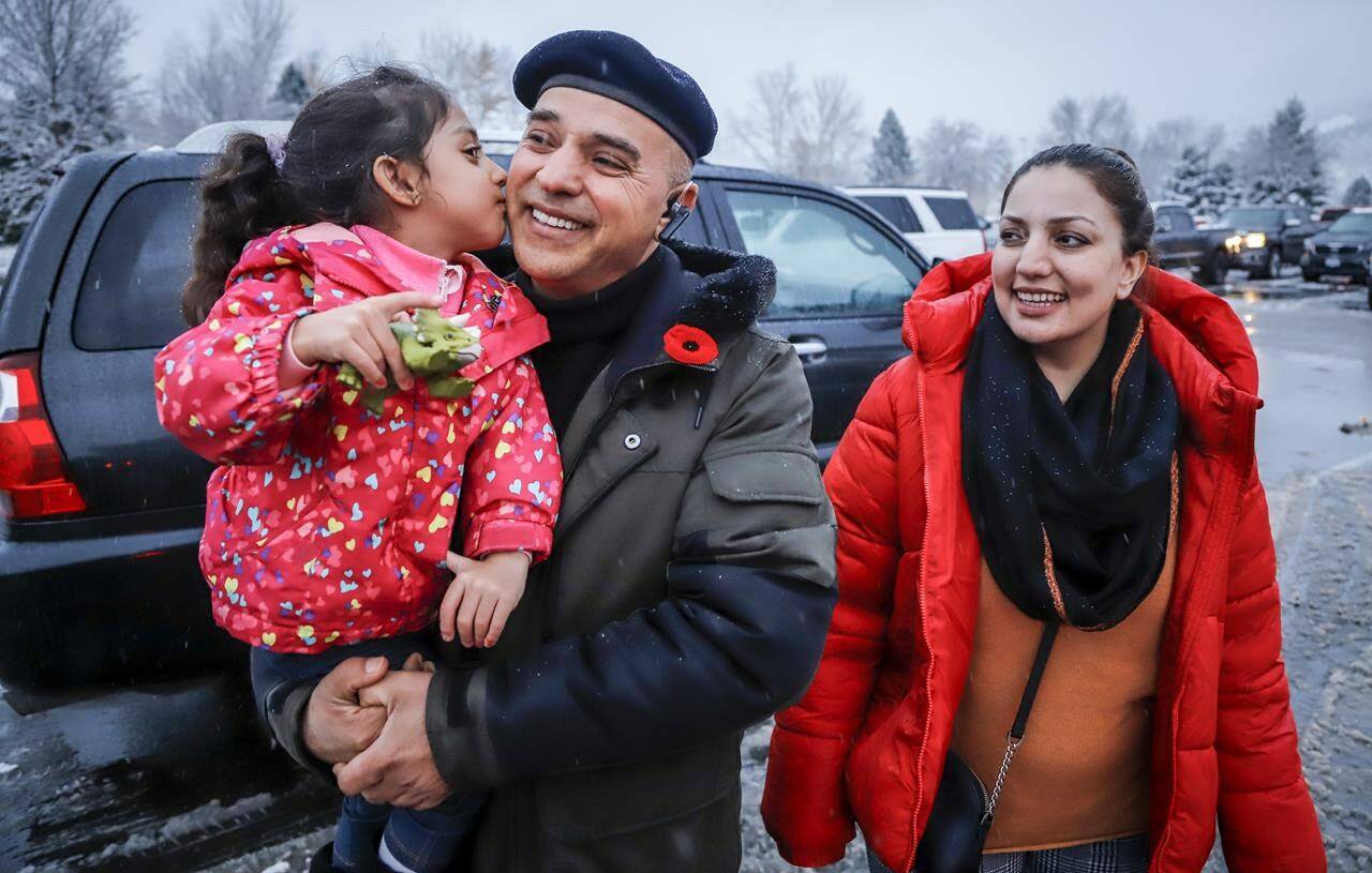 Evacuees from Merritt, B.C., Barkad Khan, centre, holds his daughter Mahira Khan, 4, as his wife Afreen Khan, looks on while they gather at a reception centre in Kamloops, B.C., Thursday, Nov. 18, 2021. THE CANADIAN PRESS/Jeff McIntosh
