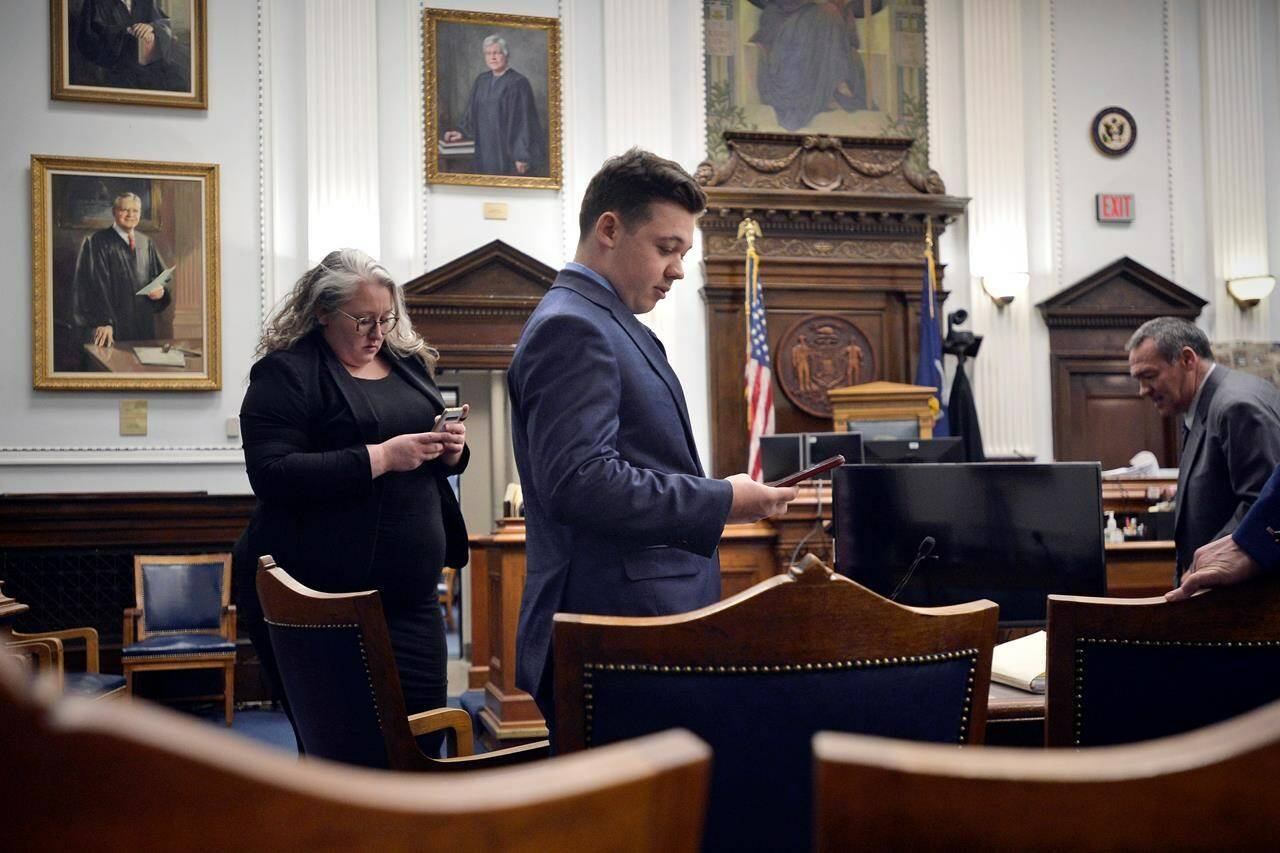 Defendant Kyle Rittenhouse checks his cell phone as he waits with his attorneys for the judge to relieve the jury during his trial at the Kenosha County Courthouse in Kenosha, Wis., on Thursday, Nov. 18, 2021. (Sean Krajacic/The Kenosha News via AP, Pool)
