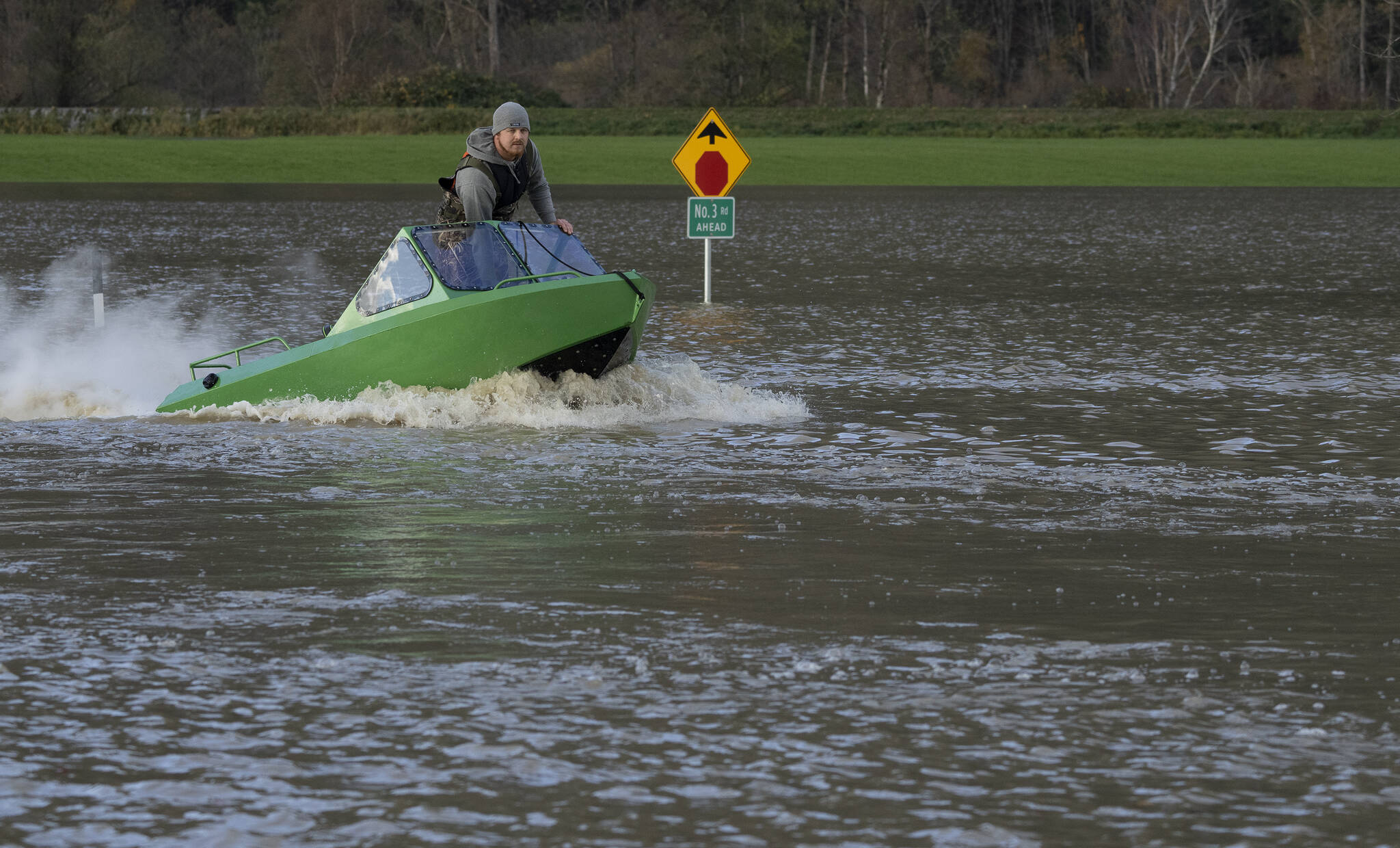 A man drives a boat down a flooded road in Chilliwack, B.C., Tuesday, November 16, 2021. THE CANADIAN PRESS/Jonathan Hayward