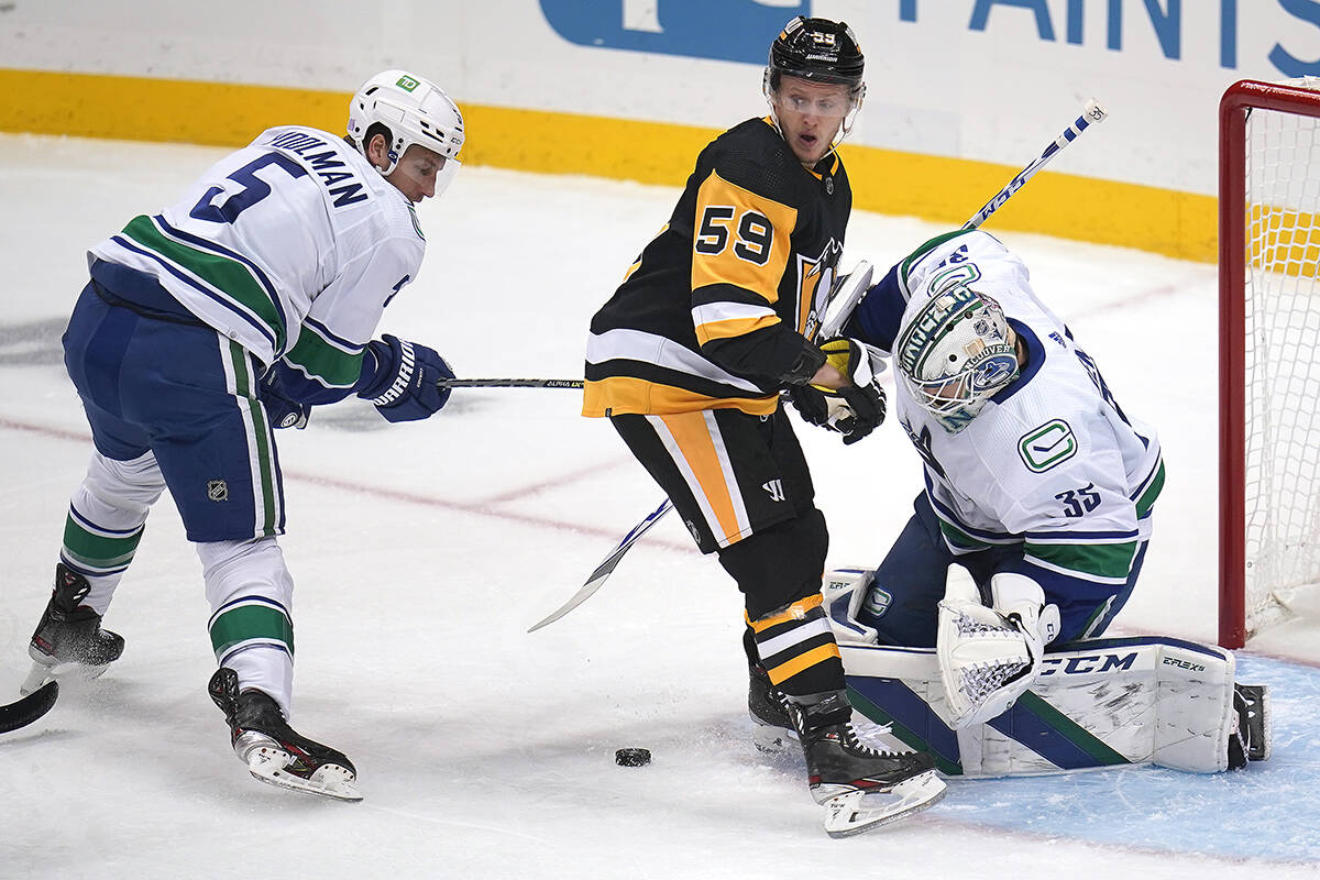 Pittsburgh Penguins’ Jake Guentzel (59) can’t find a rebound in front of Vancouver Canucks goaltender Thatcher Demko (35) with Tucker Poolman (5) defending during the first period of an NHL hockey game in Pittsburgh, Wednesday, Nov. 24, 2021. (AP Photo/Gene J. Puskar)
