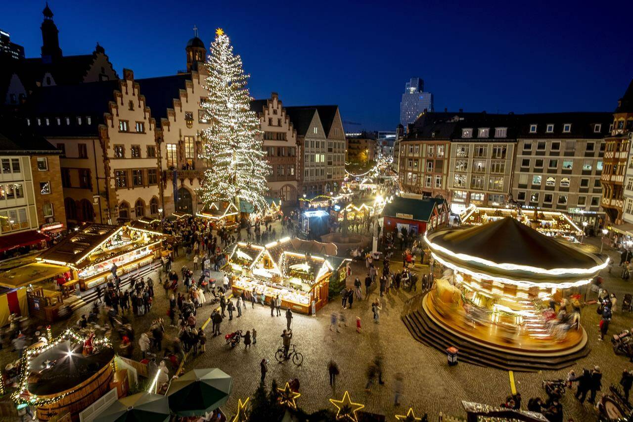 FILE - Lights illuminate the Christmas market in Frankfurt, Germany, Nov. 22, 2021. Despite the pandemic inconveniences, stall owners selling ornaments, roasted chestnuts and other holiday-themed items in Frankfurt and other European cities are relieved to be open at all for their first Christmas market in two years, especially with new restrictions taking effect in Germany, Austria and other countries as COVID-19 infections hit record highs. (AP Photo/Michael Probst, File)