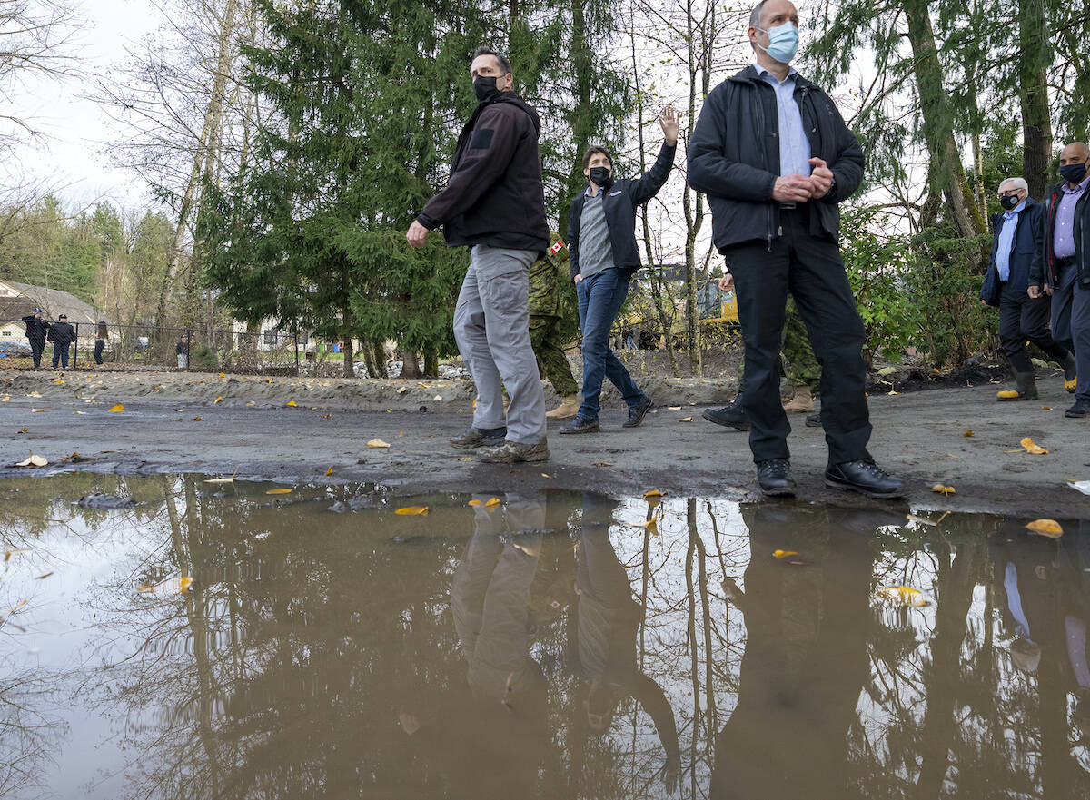 Prime Minister Justin Trudeau is reflected in a puddle as he surveys the damage left behind from the flood waters in Abbotsford, B.C., Friday, November 26, 2021. THE CANADIAN PRESS/Jonathan Hayward