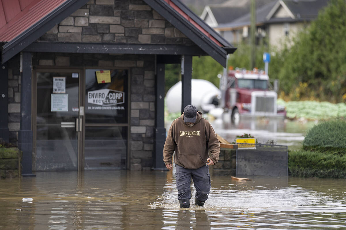 A man walks through he rising flood waters crossing into Canada from the United States in Huntington Village in Abbotsford, B.C., Monday, November 28, 2021. THE CANADIAN PRESS/Jonathan Hayward