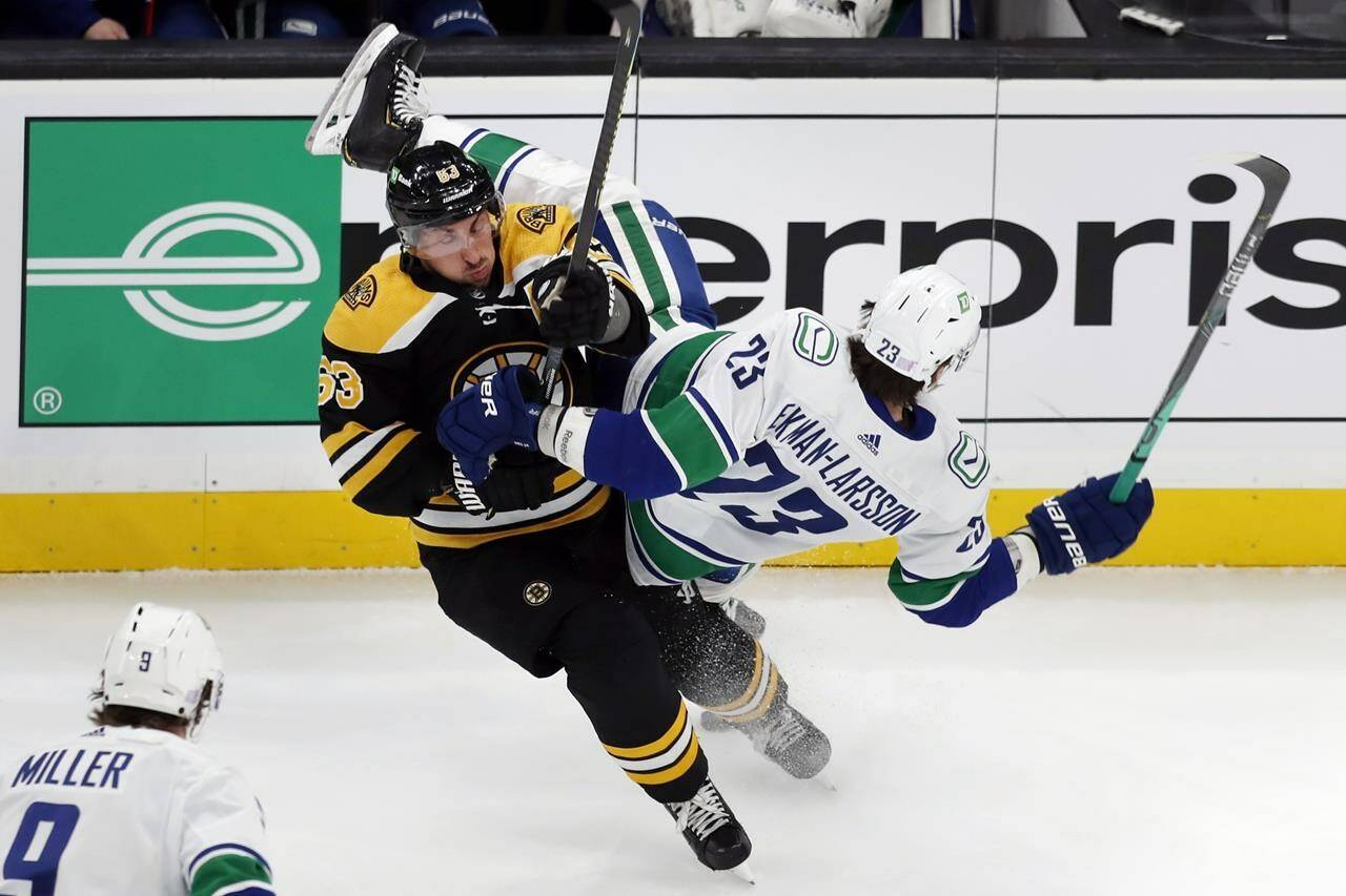 Boston Bruins’ Brad Marchand (63) checks Vancouver Canucks’ Oliver Ekman-Larsson (23) during the first period of an NHL hockey game, Sunday, Nov. 28, 2021, in Boston. (AP Photo/Michael Dwyer)