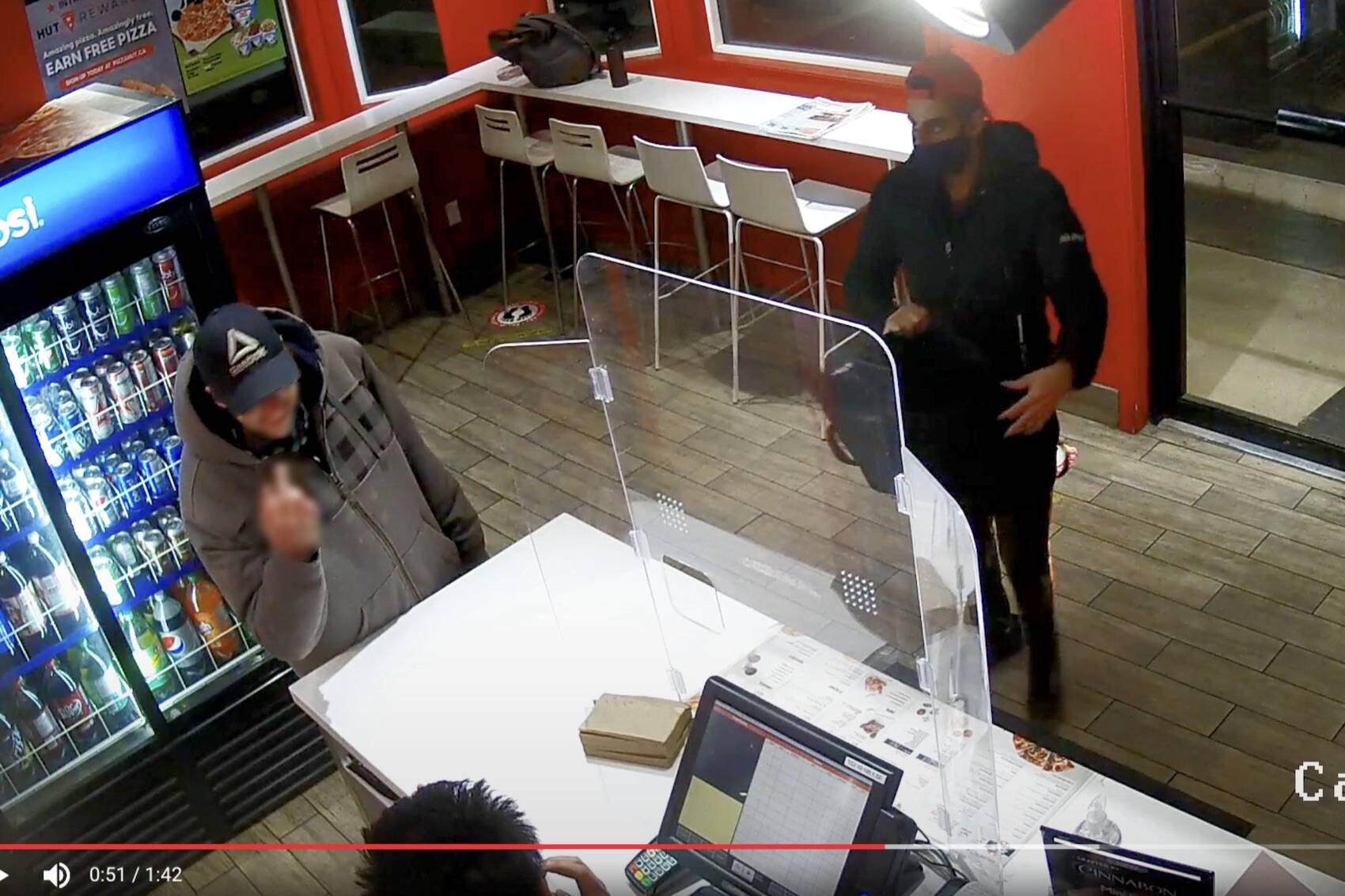 A still from security camera footage shows a man making a rude hand gesture towards a Salmon Arm Pizza Hut employee during an exchange in which racist comments were allegedly made towards the restaurant’s staff Monday night, Nov. 29, 2021. (Contributed)