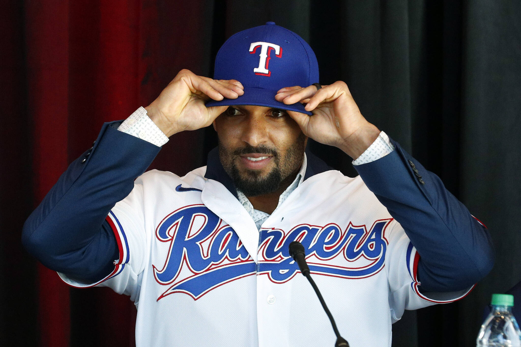 New Texas Rangers infielder Marcus Semien adjusts his hat as he gets ready to answer questions at a press conference at Globe Life Field Wednesday, Dec. 1, 2021, in Arlington, Texas. (AP Photo/Richard W. Rodriguez)