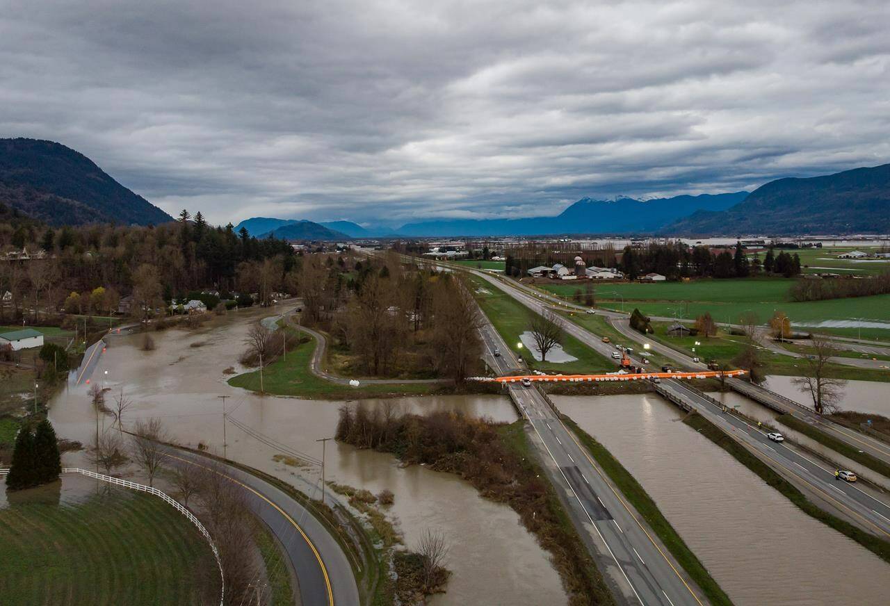 A Tiger Dam is placed across all lanes of the closed Trans-Canada Highway near the flooded Sumas River, in Abbotsford, B.C., on Wednesday, December 1, 2021. THE CANADIAN PRESS/Darryl Dyck