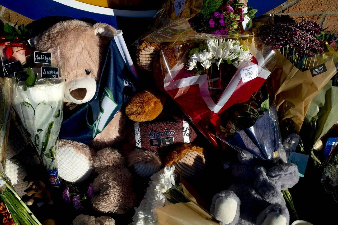 A football is left in honor of Tate Myre, one of the four victims who was killed in Tuesday’s school shooting, at a memorial where family, friends, students and relatives of victims put up bouquets of flowers, candles and personalized messages near an entrance to the Oxford High School on Thursday, Dec. 2, 2021 in Oxford, Mich. A 15-year-old boy has been denied bail and moved to jail after being charged in the Michigan school shooting that killed four students and injured others.(Jake May/The Flint Journal via AP)