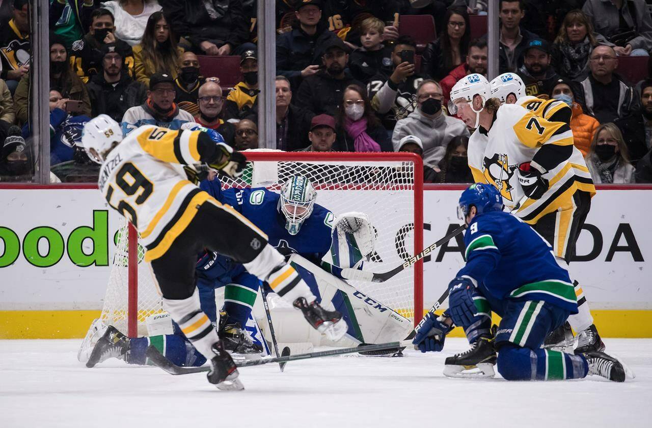 Pittsburgh Penguins’ Jake Guentzel, front left, scores his third goal against Vancouver Canucks goalie Thatcher Demko, back centre, during the second period of an NHL hockey game in Vancouver, on Saturday, December 4, 2021. THE CANADIAN PRESS/Darryl Dyck