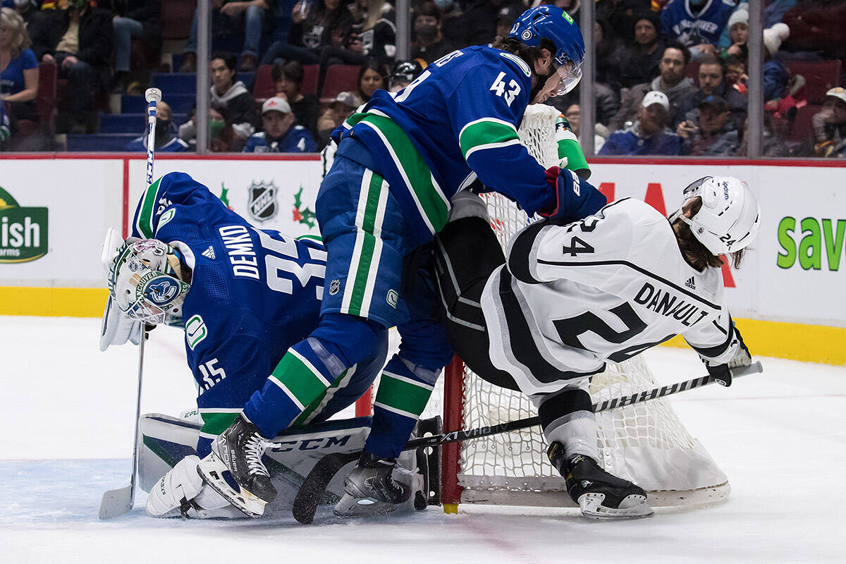 Vancouver Canucks goalie Thatcher Demko (35) covers up the puck as Quinn Hughes (43) checks Los Angeles Kings’ Phillip Danault (24) during first period NHL hockey action in Vancouver, B.C., Monday, Dec. 6, 2021. THE CANADIAN PRESS/Darryl Dyck